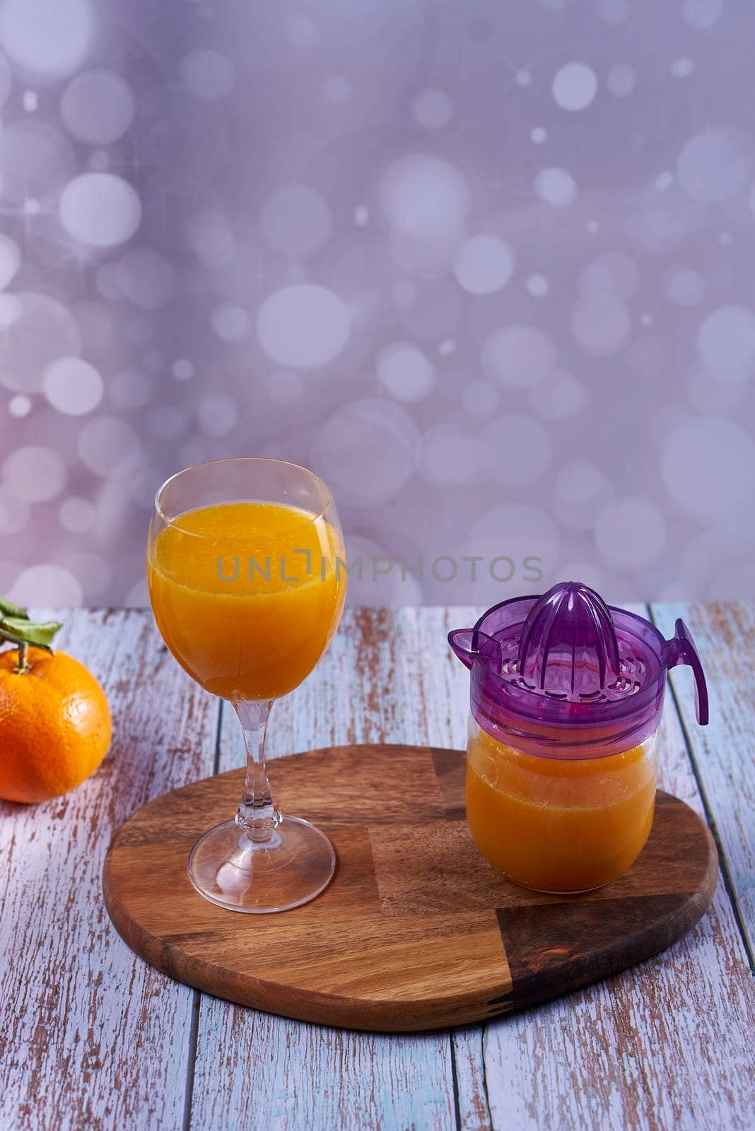 Glass of orange juice. glass juicer, wooden table whole oranges with green leaves bright background