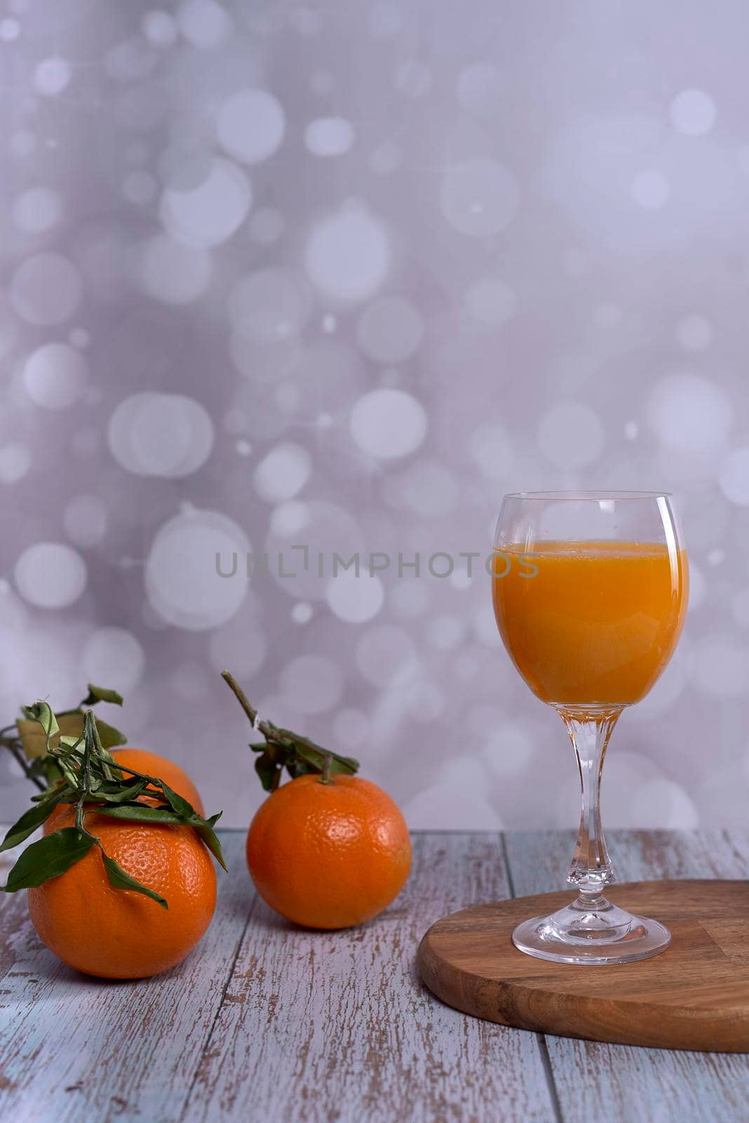 Glass of orange juice. wooden table whole oranges with green leaves bright background