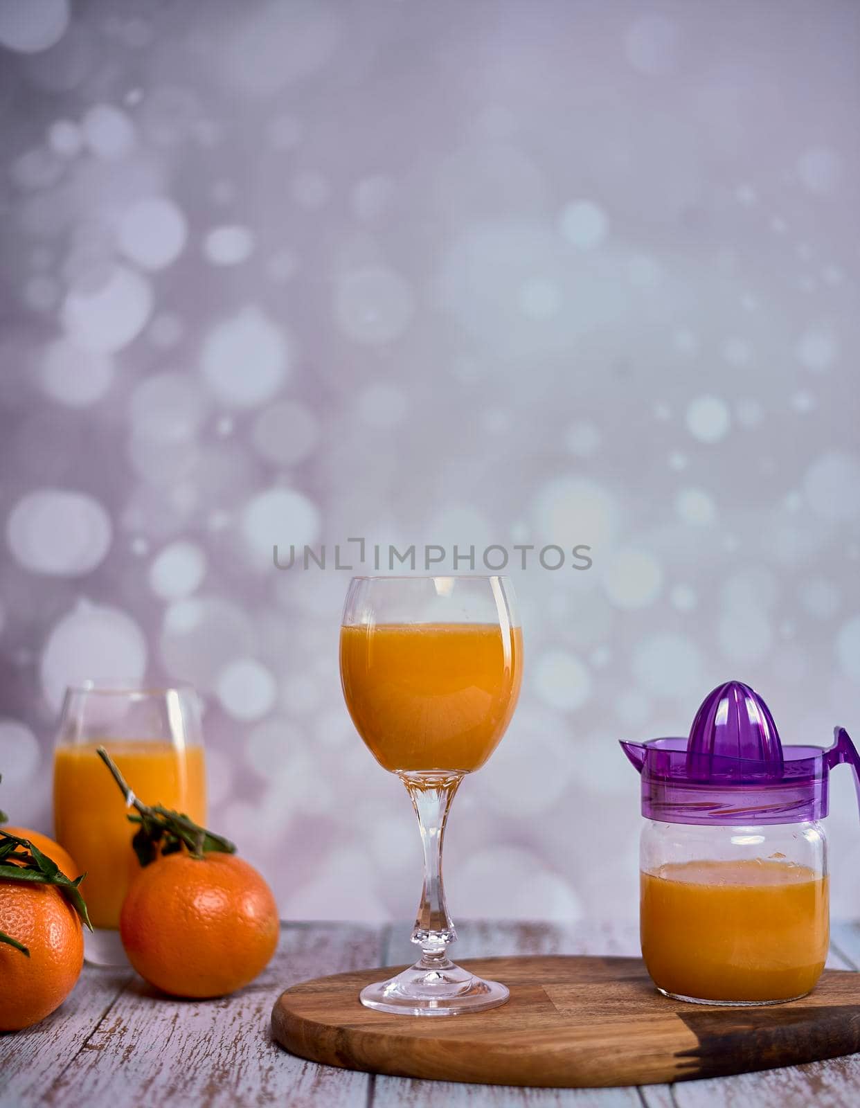 Glass of orange juice. glass juicer, orange juice, wooden table whole oranges with green leaves bright background