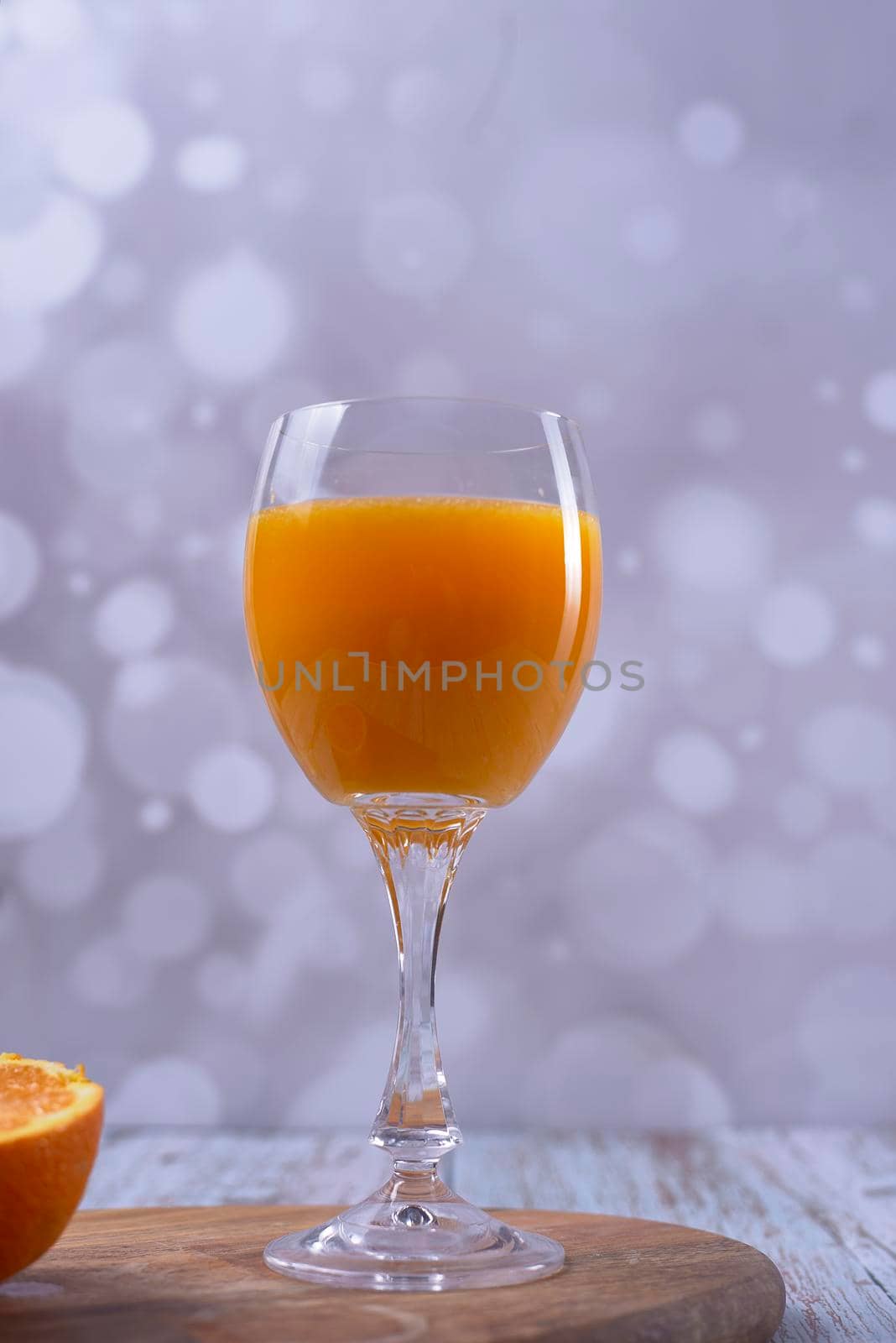 Glass of orange juice on wooden table bright background, front view