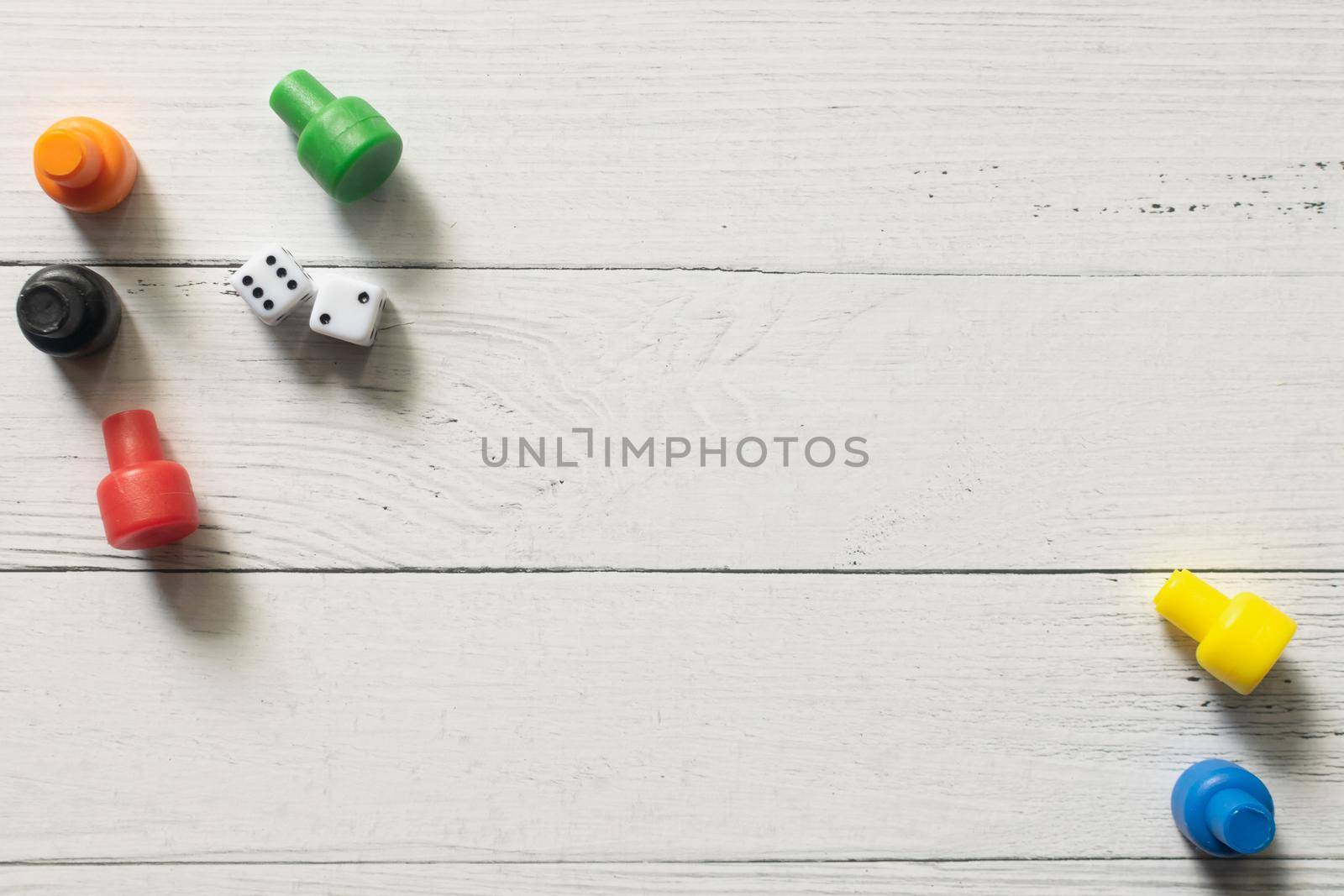 Multi-colored game chips with dices on wooden board. Board game.