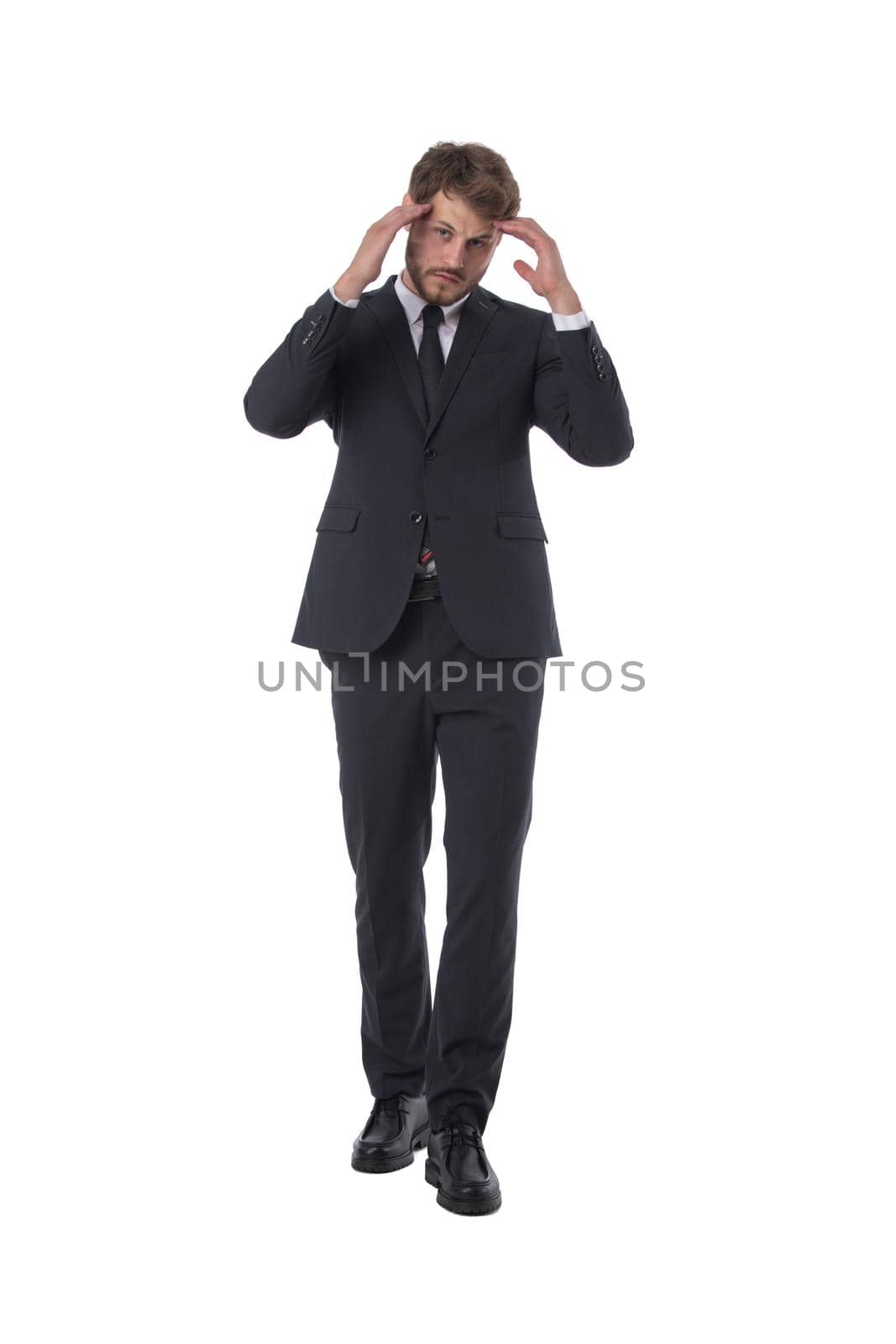 Handsome business man standing in a suit and tie holding his hands behind his head, isolated on white background, headache problem solution thinking concept