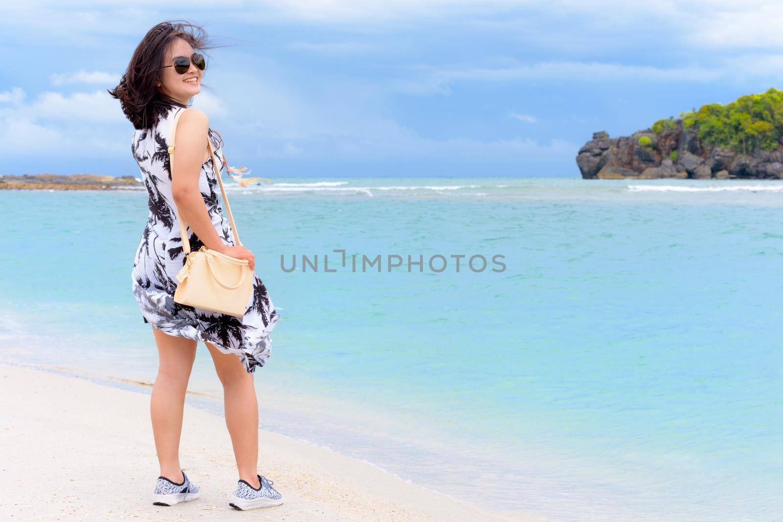 Beautiful nature landscape and cute teen girl tourist wearing sunglasse shoulder bag fashion smiling with happy on the beach and sea in summer at Tarutao island, Satun, Thailand