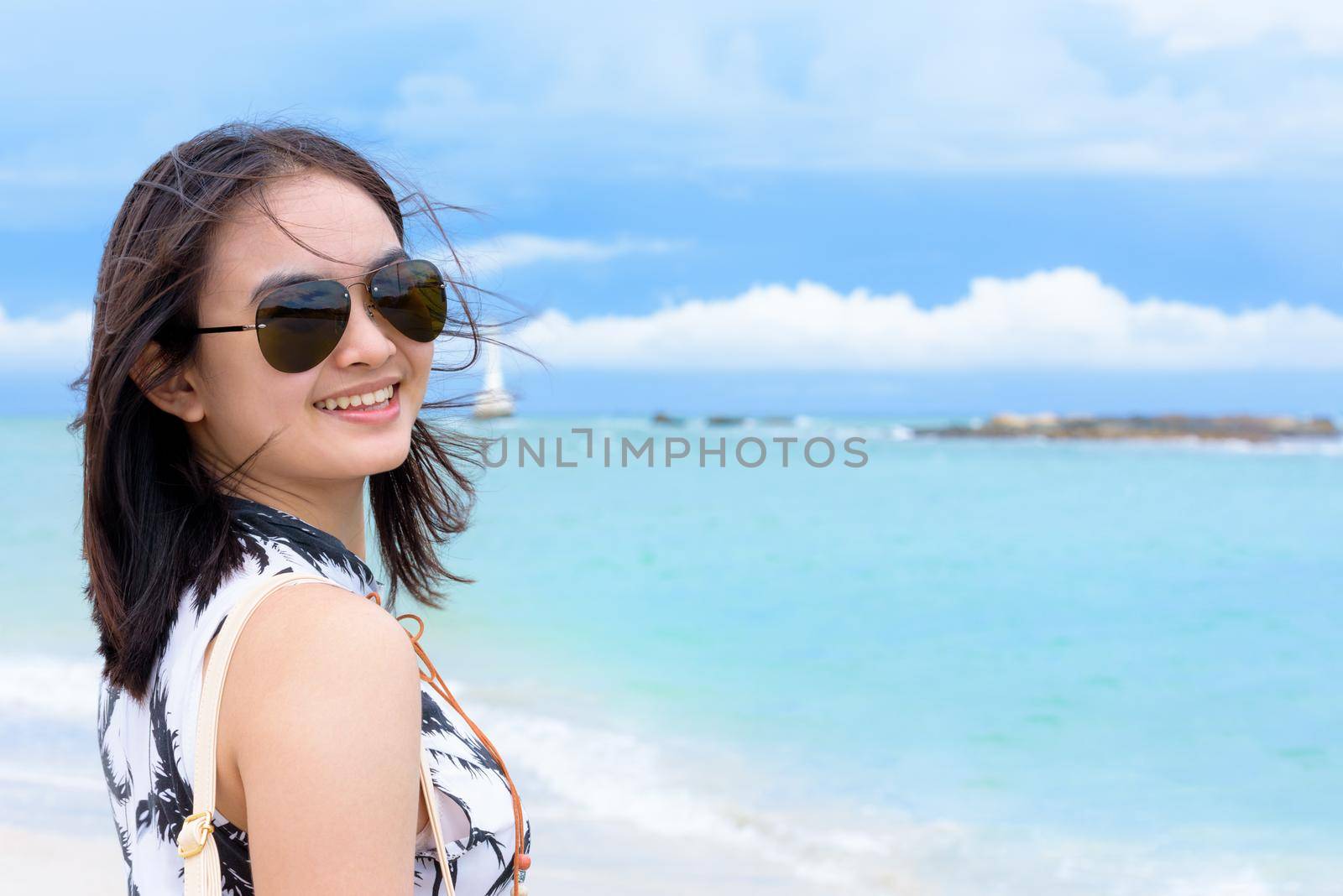 Beautiful woman tourist wearing sunglasse looking at the camera and smiling with happy on the beach and sea in summer sky background at Koh Tarutao island, Satun, Thailand