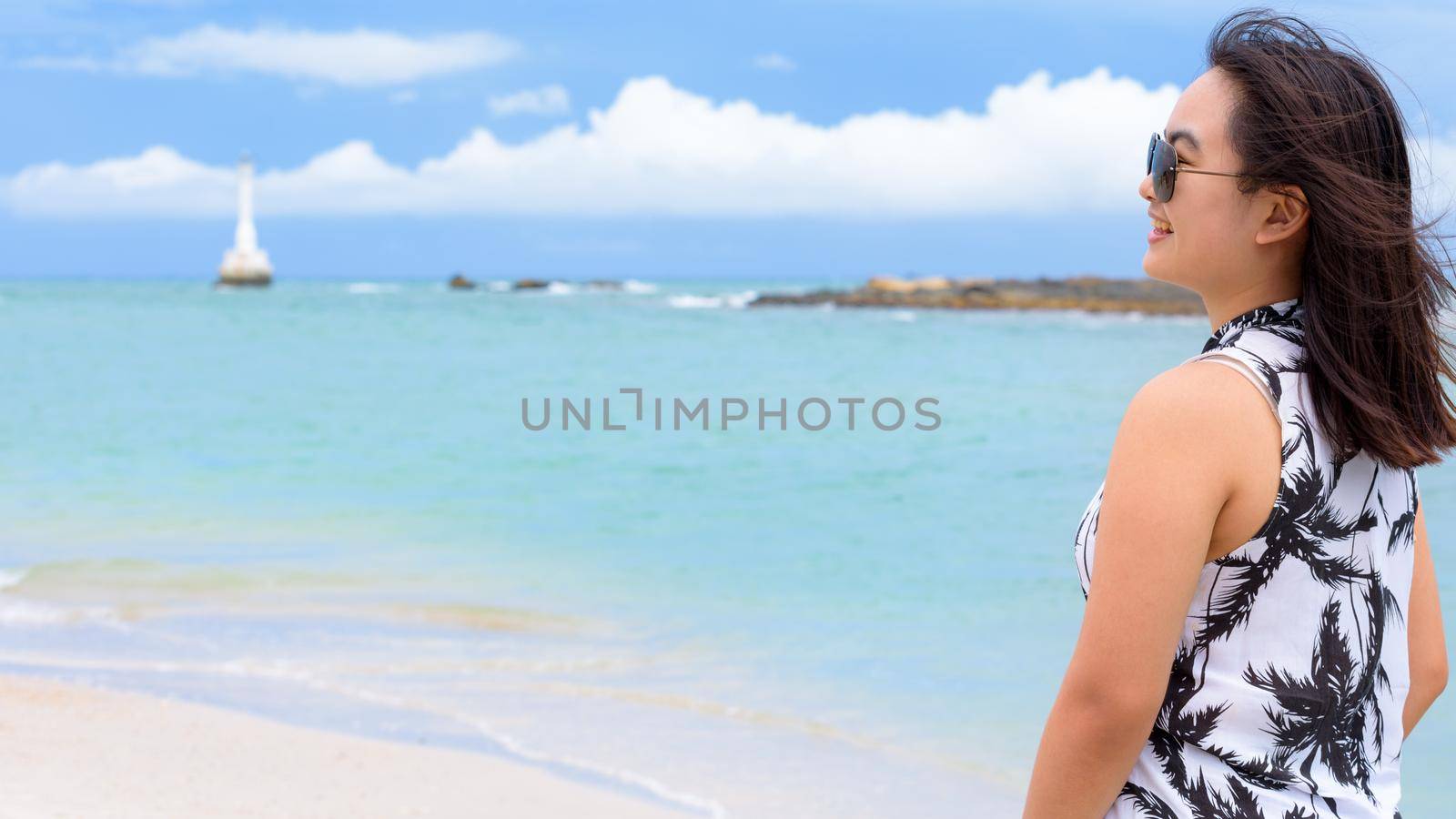 Woman tourist wearing sunglasse looking at beautiful nature landscape of the beach and sea in summer sky background at Tarutao island, Satun, Thailand, 16:9 widescreen