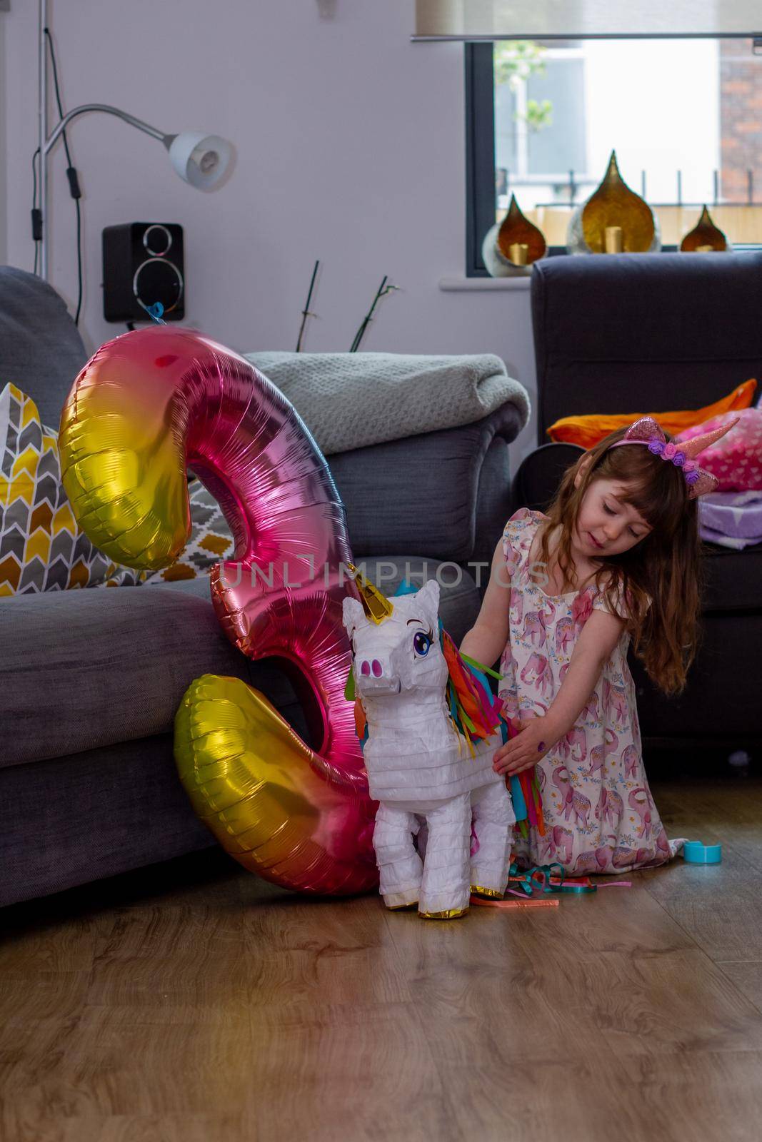 A Cute Baby Girl Sitting On The Floor With a Balloon And An Unicorn Pinata by AlbertoPascual