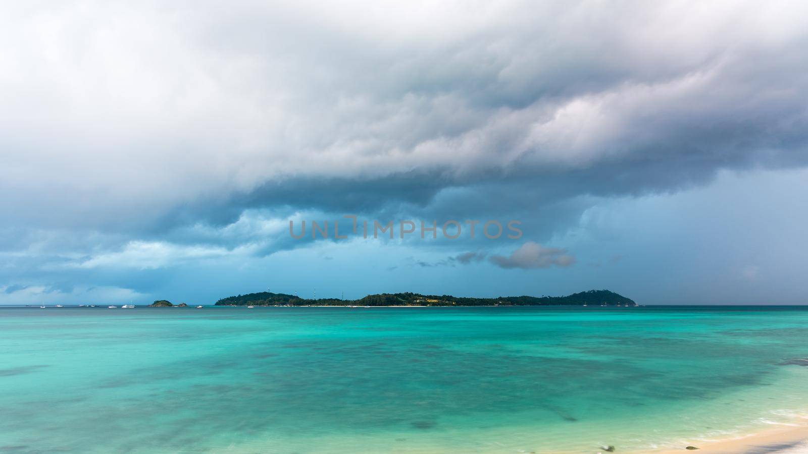Climate change with storm clouds and rain over Koh Lipe island and the green waters of the Andaman Sea, is a famous attractions of Tarutao National Park, Satun, Thailand, 16:9 widescreen