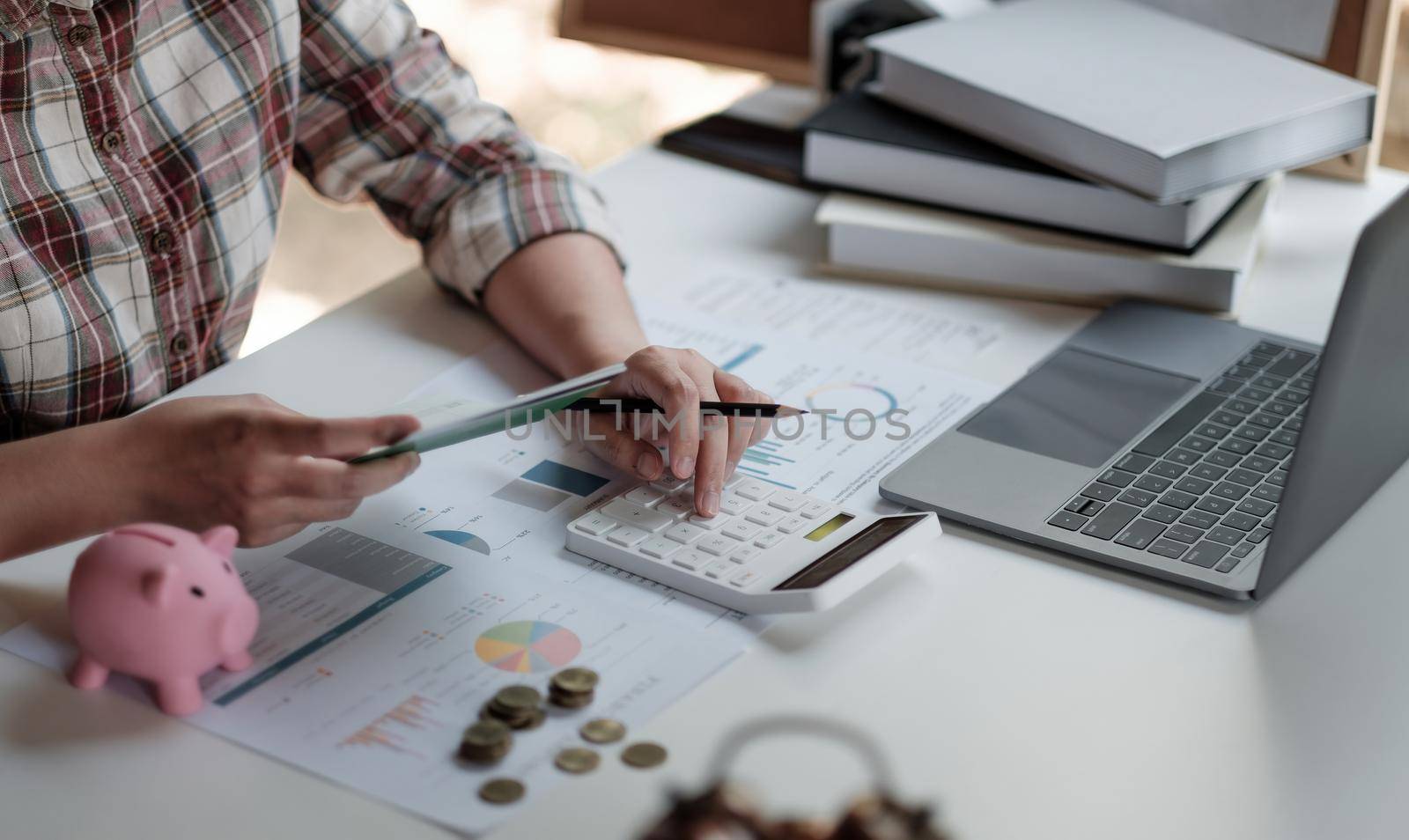 Woman calculating her Debt. woman hand calculating her monthly expenses during tax season with coins, calculator and account bank