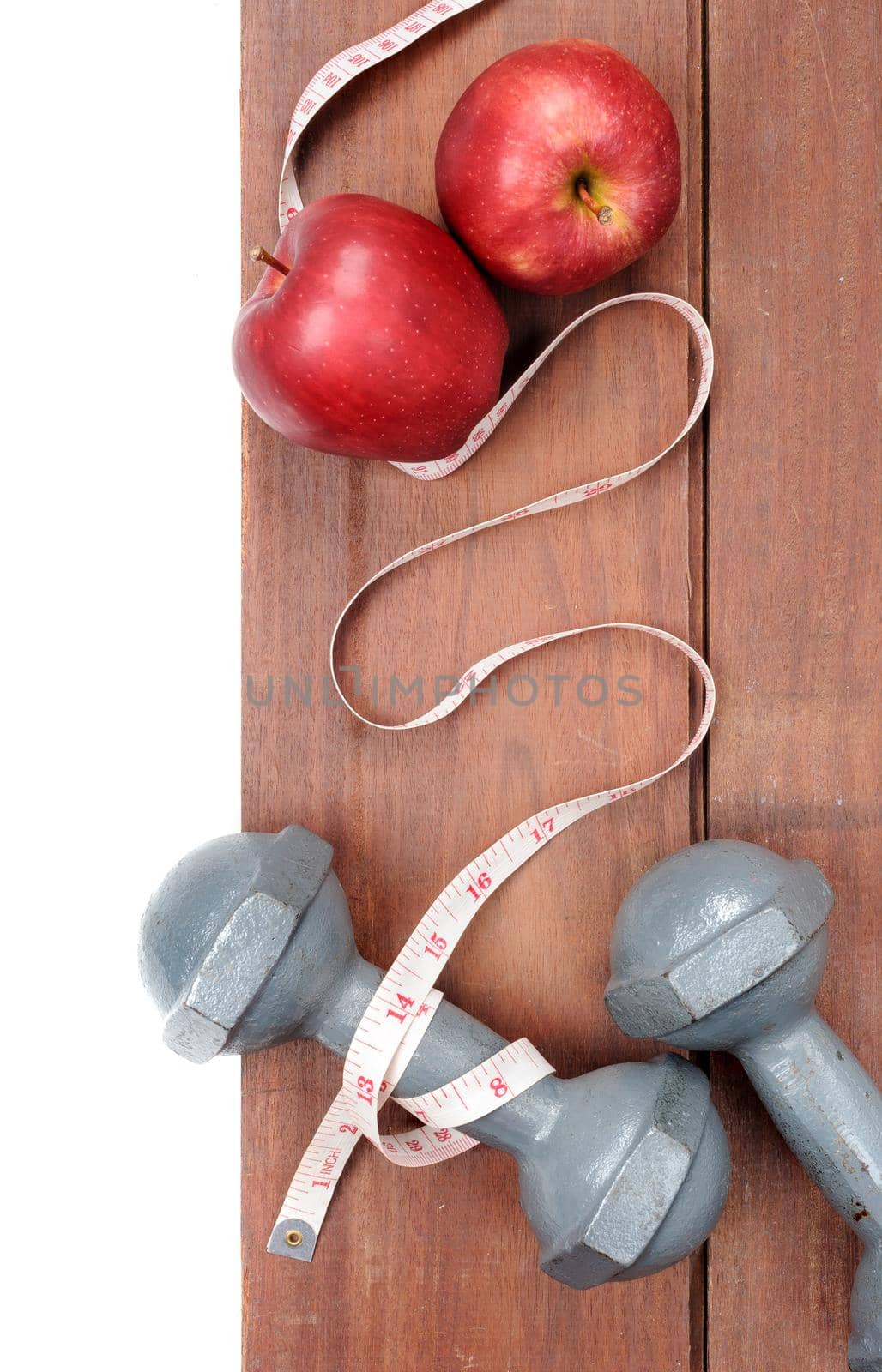 closeup fresh ripe red apples dumbbells and tape measure on wooden plank