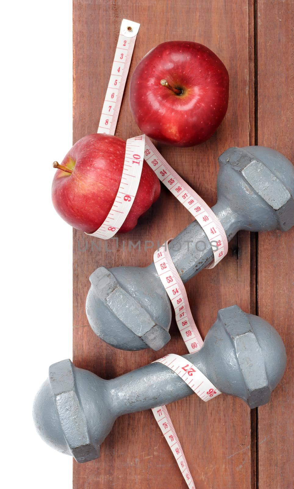 closeup fresh ripe red apples dumbbells and tape measure on wooden plank