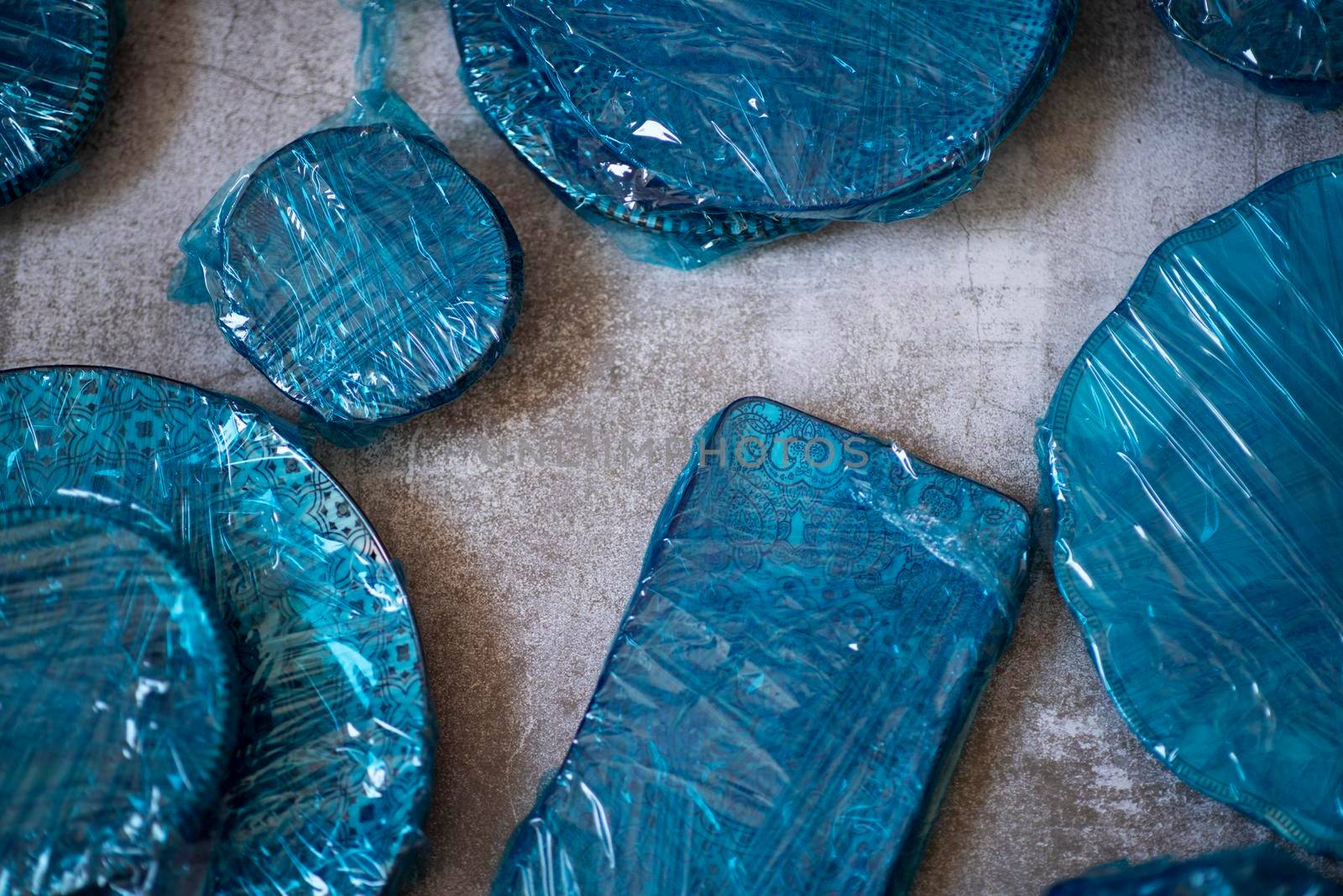 Small plates wrapped in blue cling film placed on brown wooden floor background. Top view. Copy Space. High quality photo