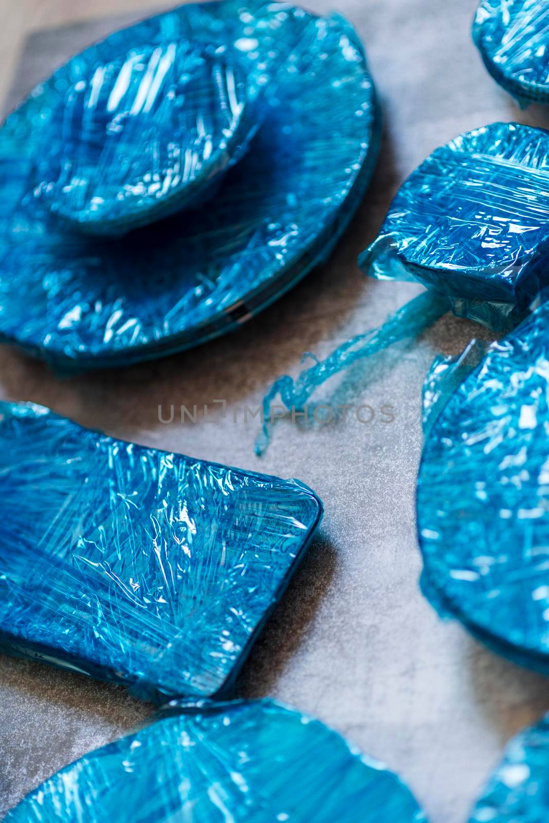 Small plates wrapped in blue cling film placed on brown wooden floor background. Top view. Copy Space. High quality photo