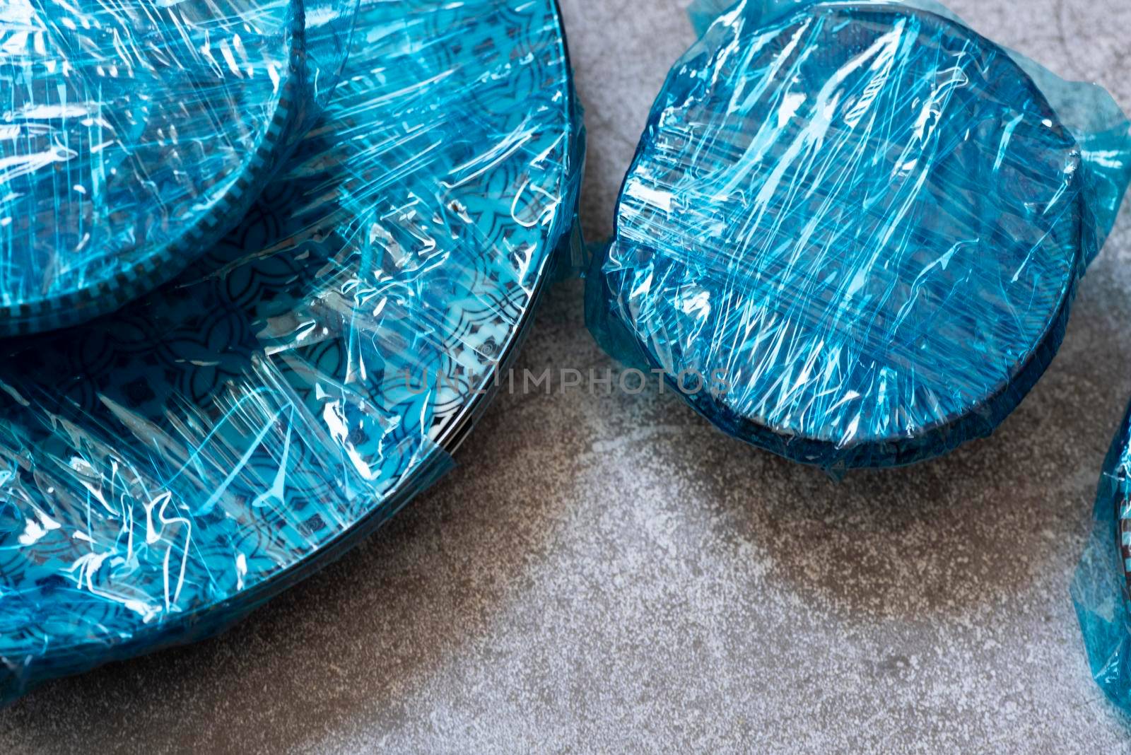 Small plates wrapped in blue cling film placed on brown wooden floor background. Top view. Copy Space. High quality photo