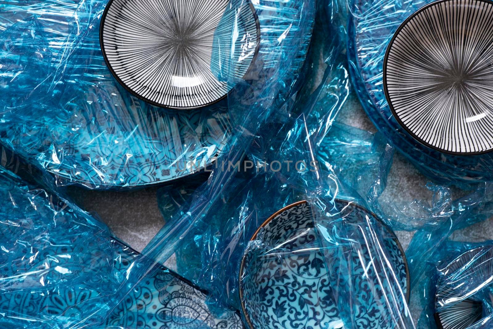 Small plates wrapped in blue cling film placed on brown wooden floor background. Top view. Copy Space. High quality photo