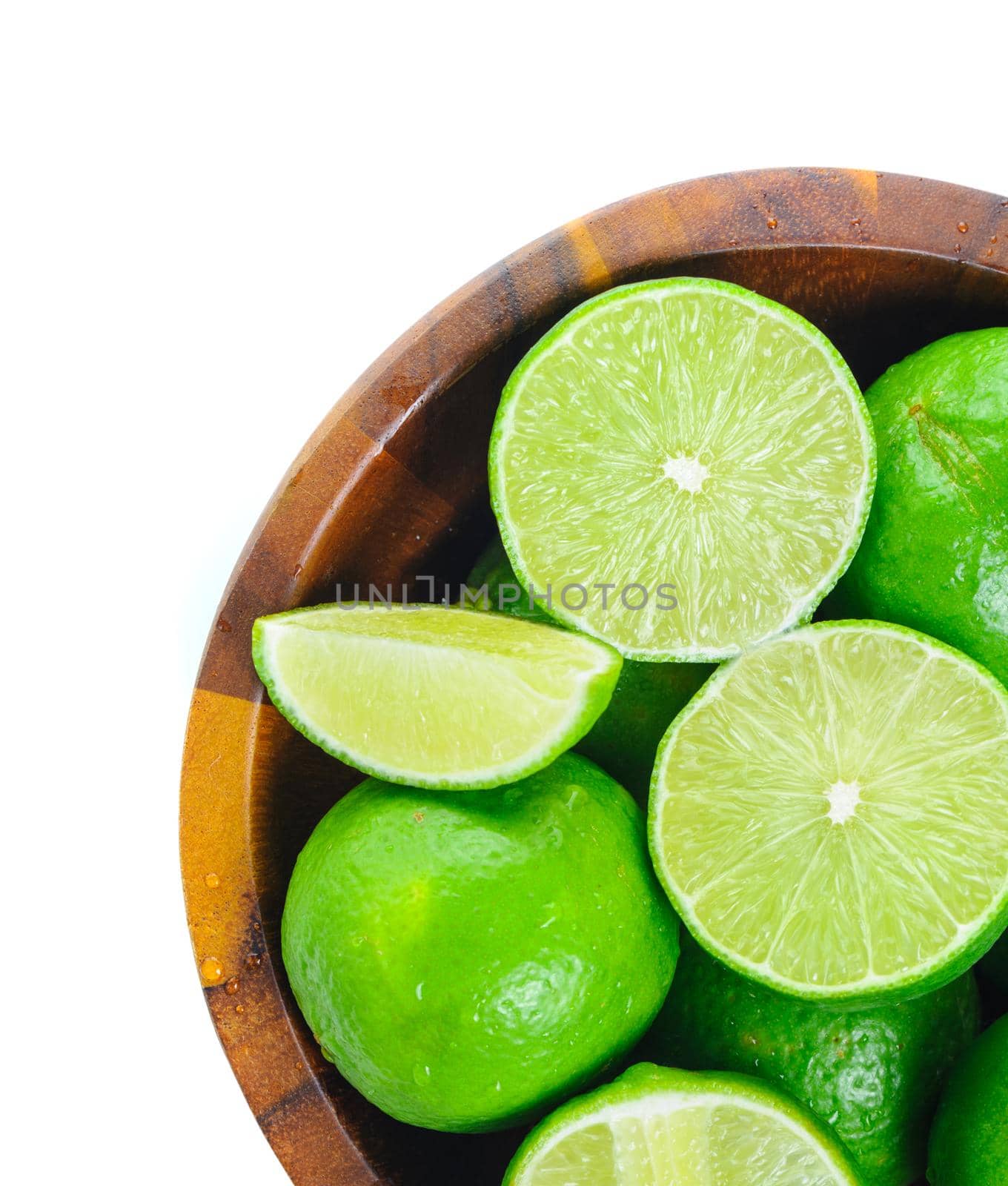fresh green limes in wooden bowl isolated on white background