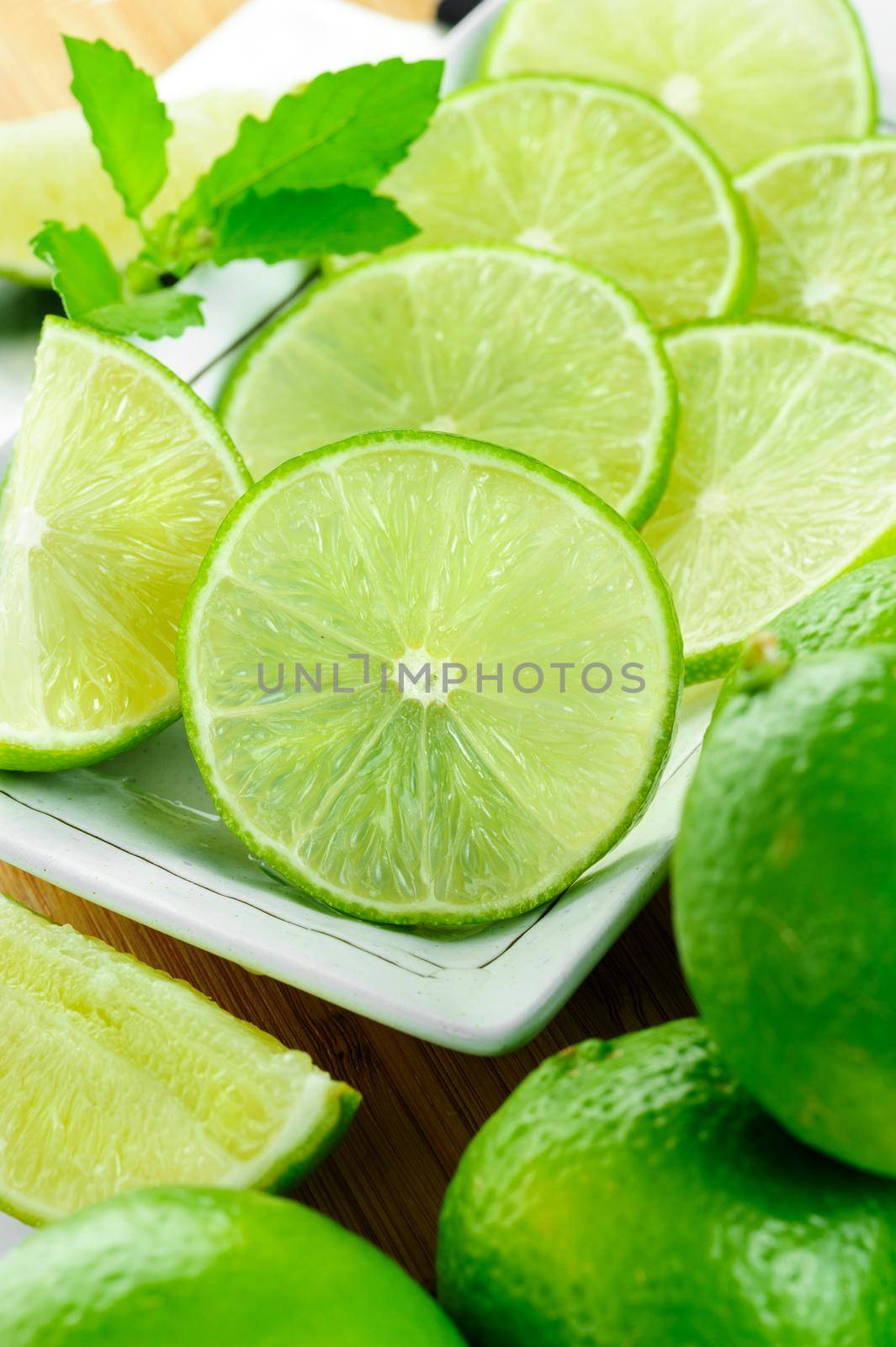 closeup sliced fresh green limes in white plate