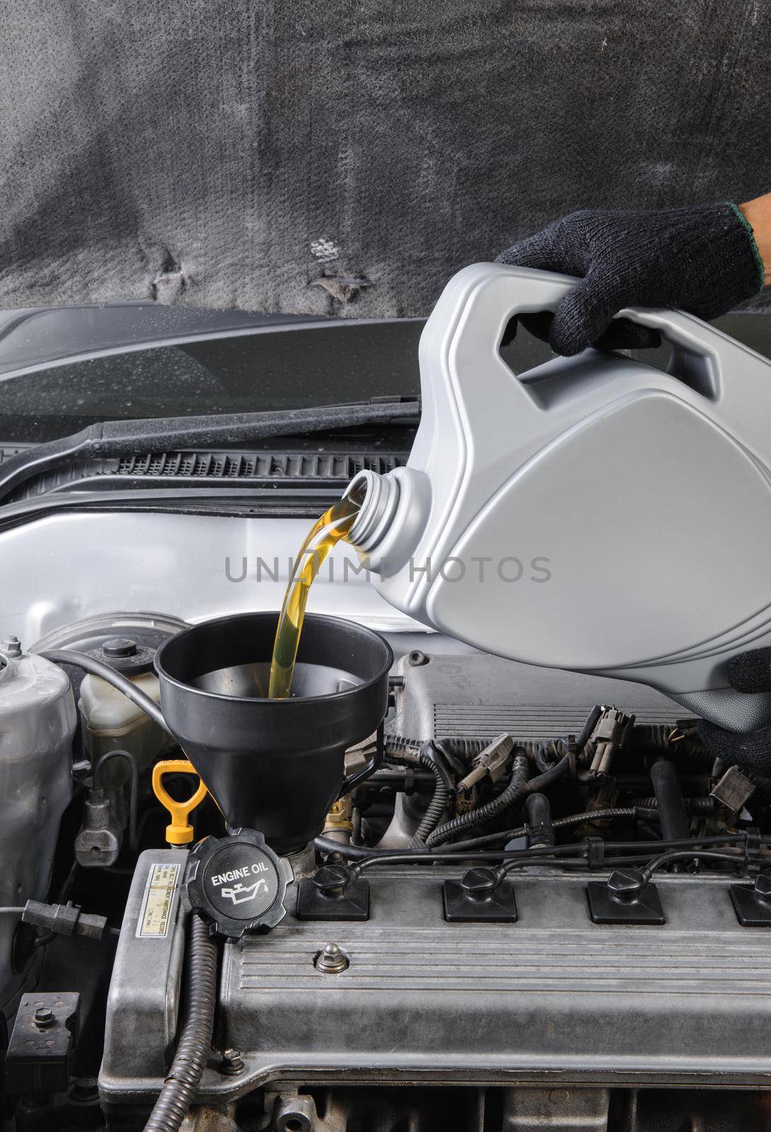 technician pouring fresh motor oil to engine of old car