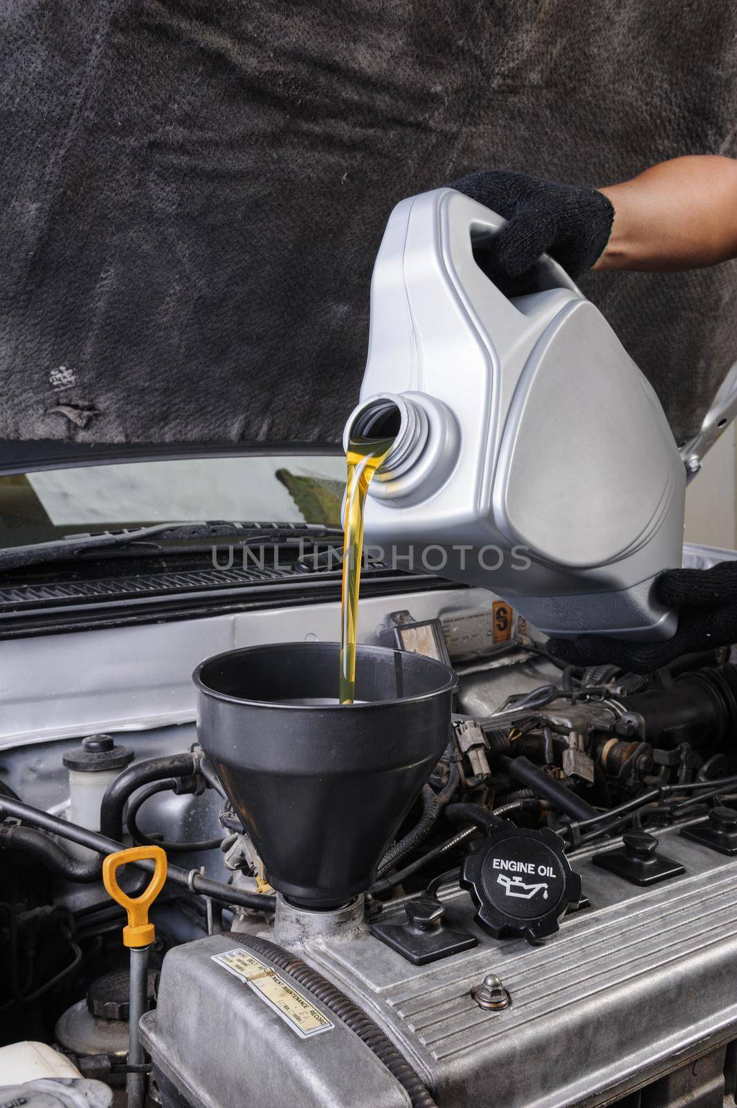 technician pouring fresh motor oil to engine of old car