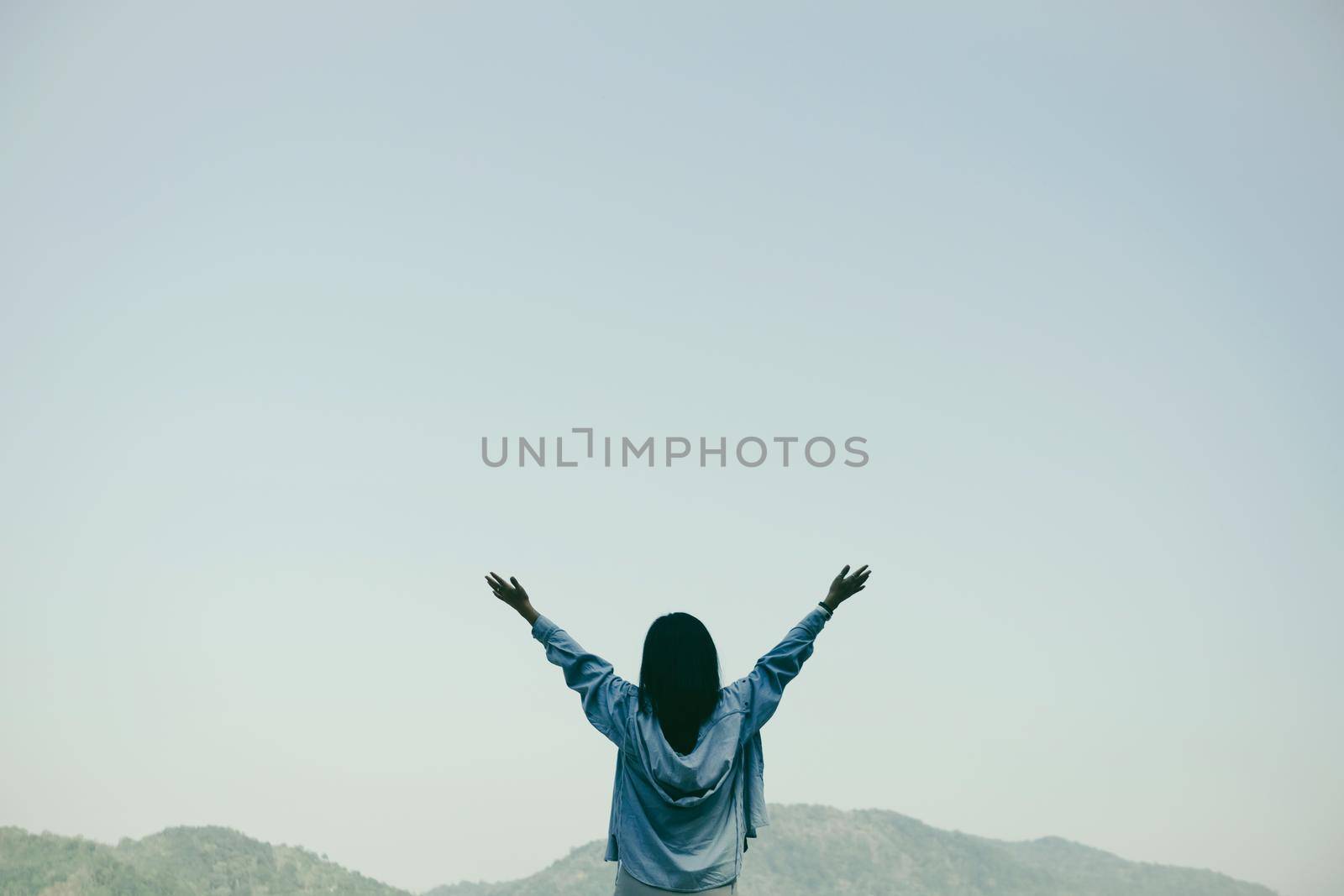 Woman rise hands up to sky freedom concept with blue sky and summer mountain background by Suwant