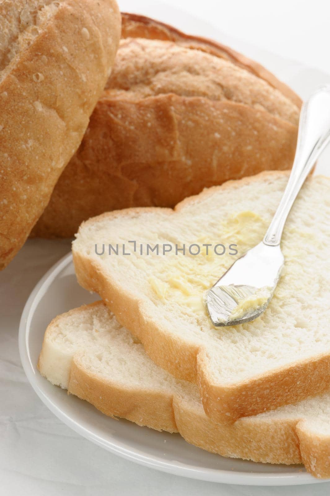 isolate sliced bread with butter on white plate