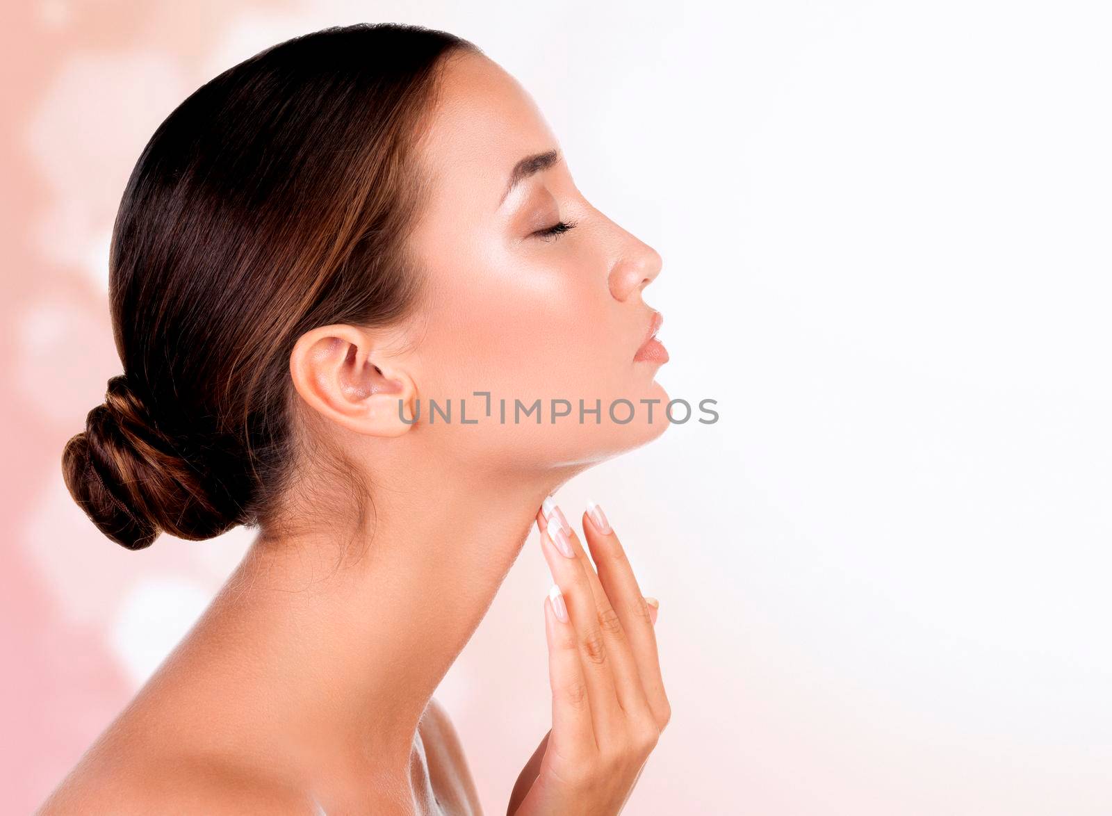 Pretty woman touches her neck against an abstract background with blurred lights