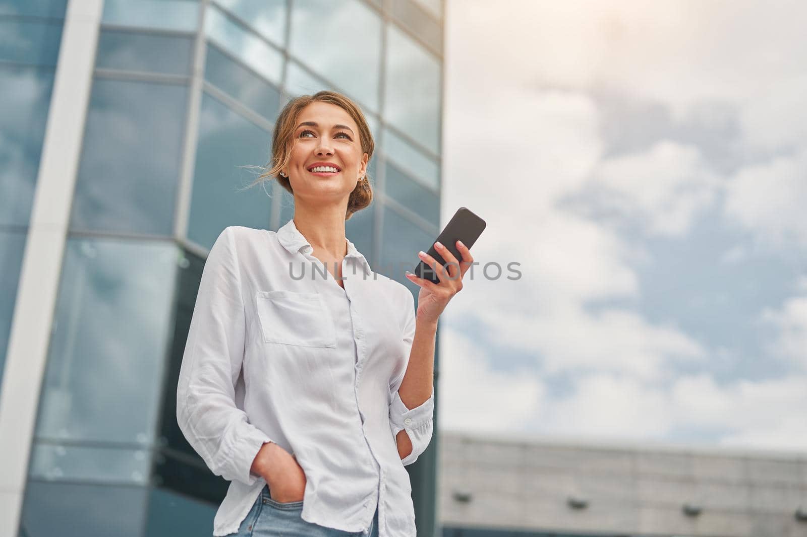 Businesswoman successful woman business person standing outdoor corporate building exterior cell phone Pensive elegance cute caucasian professional business woman middle age dreaming with mobile phone