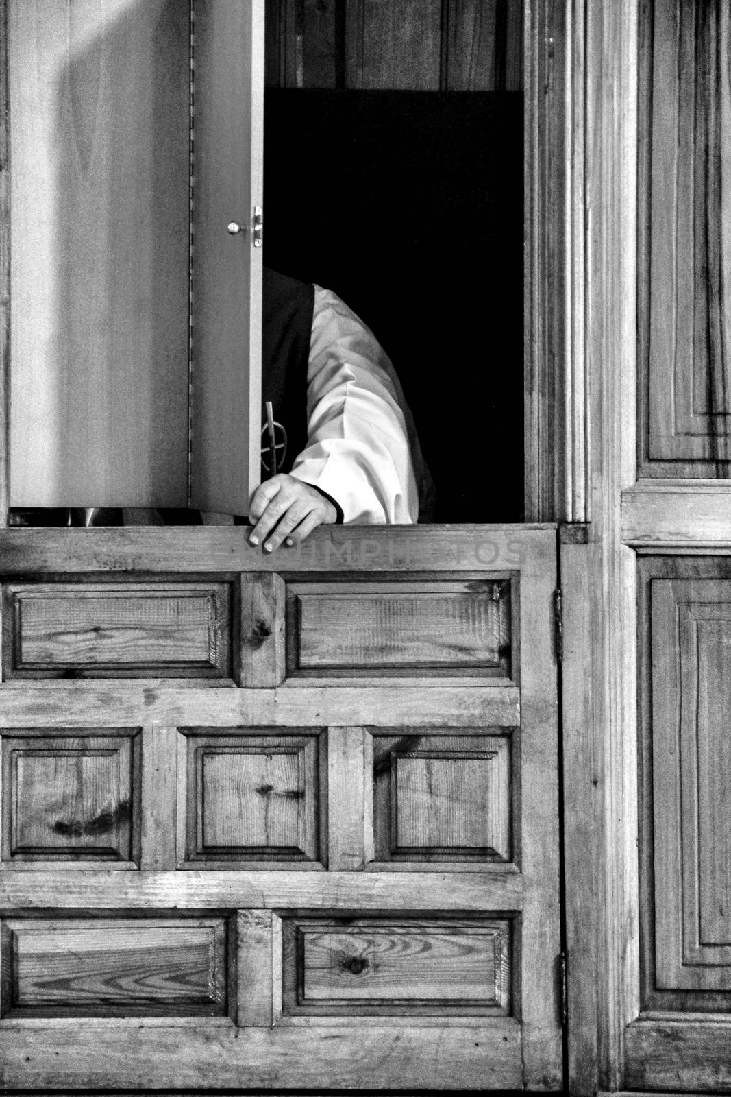 Priest in confessional confessing to a faithful in Spain