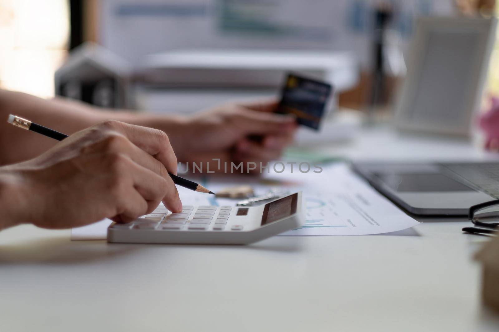 Close up man using calculator and holding credit card at home