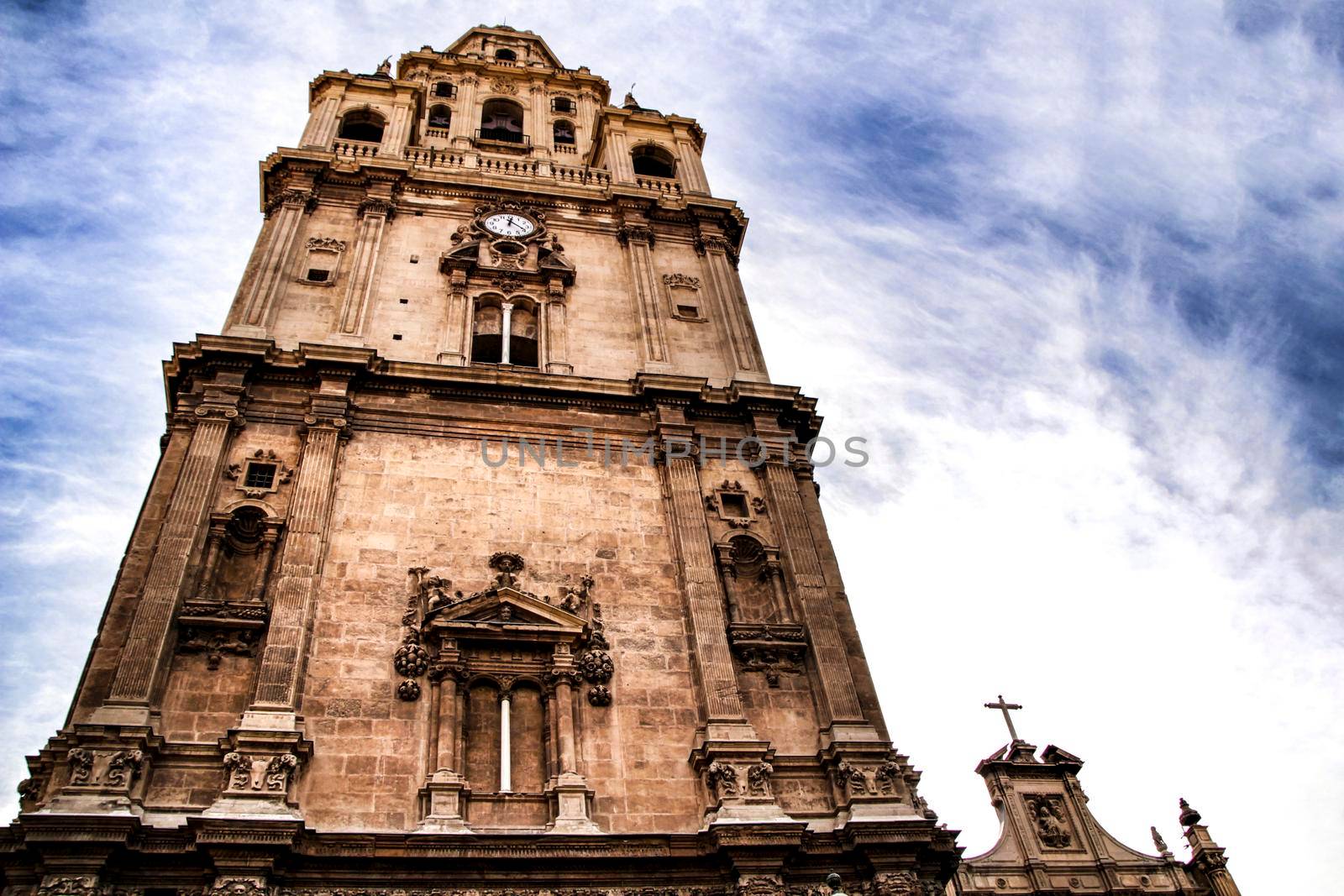 Tower bell, clock and carved stone details on the facade of the Cathedral of Murcia.