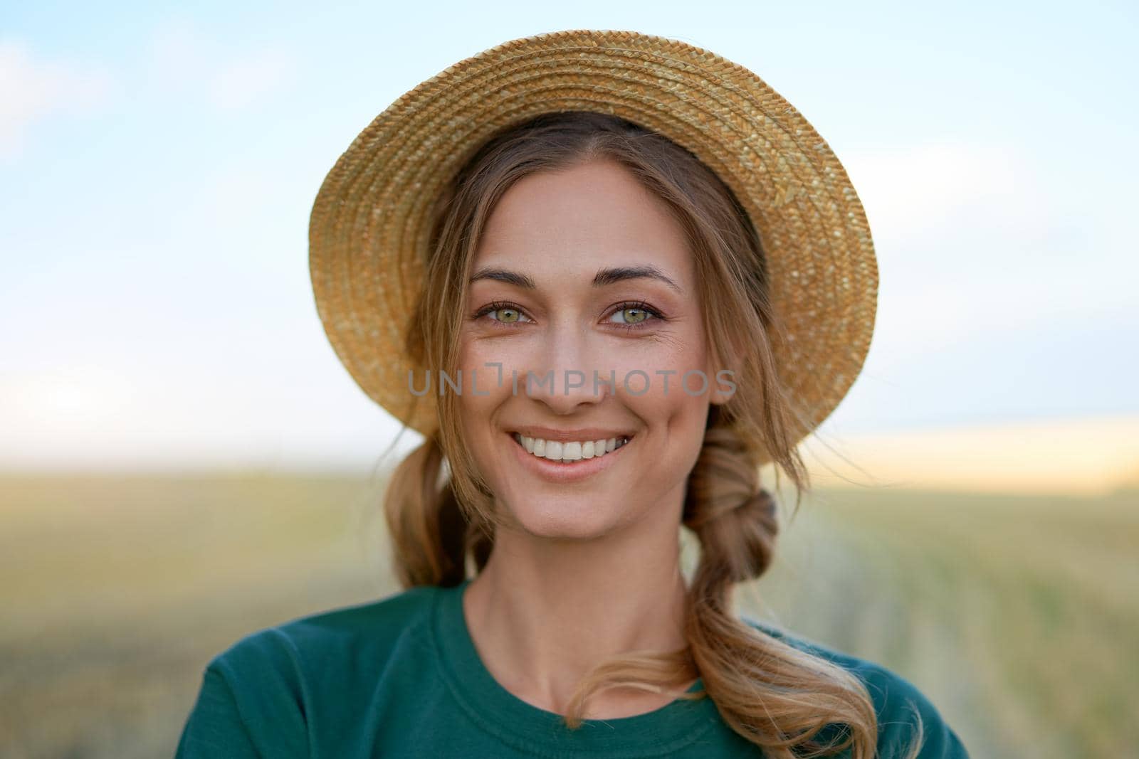 Woman farmer straw hat standing farmland smiling Female agronomist specialist farming agribusiness Happy positive caucasian worker agricultural field Pretty girl denim jeans green t-shirt harvest