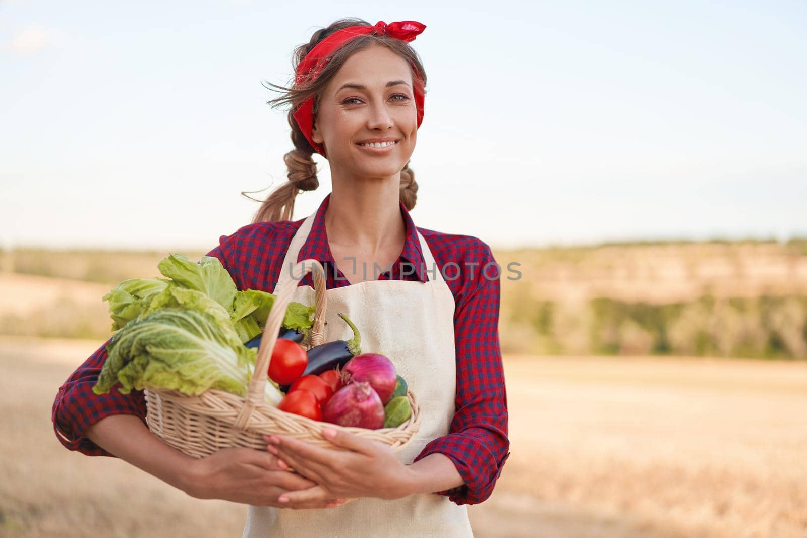 Woman farmer holding basket vegetable onion tomato salad cucumber standing farmland smiling Female agronomist specialist farming agribusiness Pretty girl dressed red checkered shirt and bandana