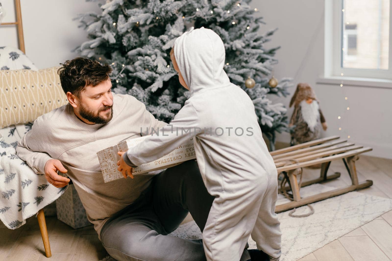 Holiday Christmas Handsome father playing with small cute son near decorated New year tree at home. High quality photo