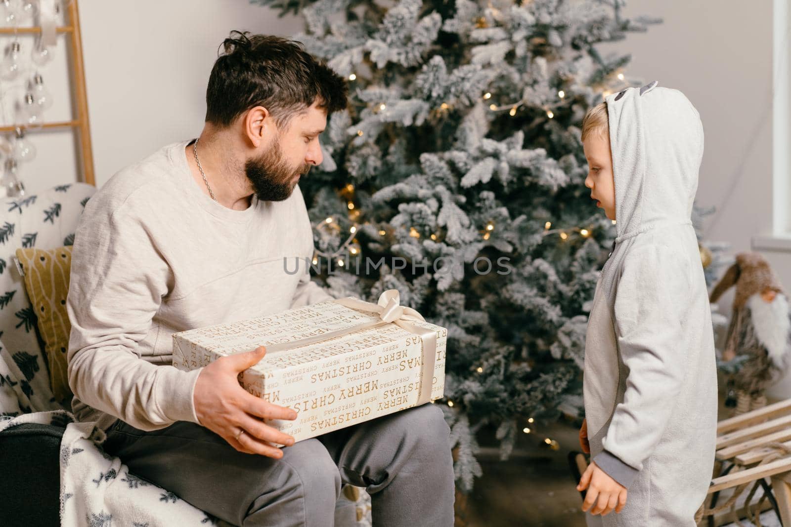Holiday Christmas Handsome father playing with small cute son near decorated New year tree at home. High quality photo