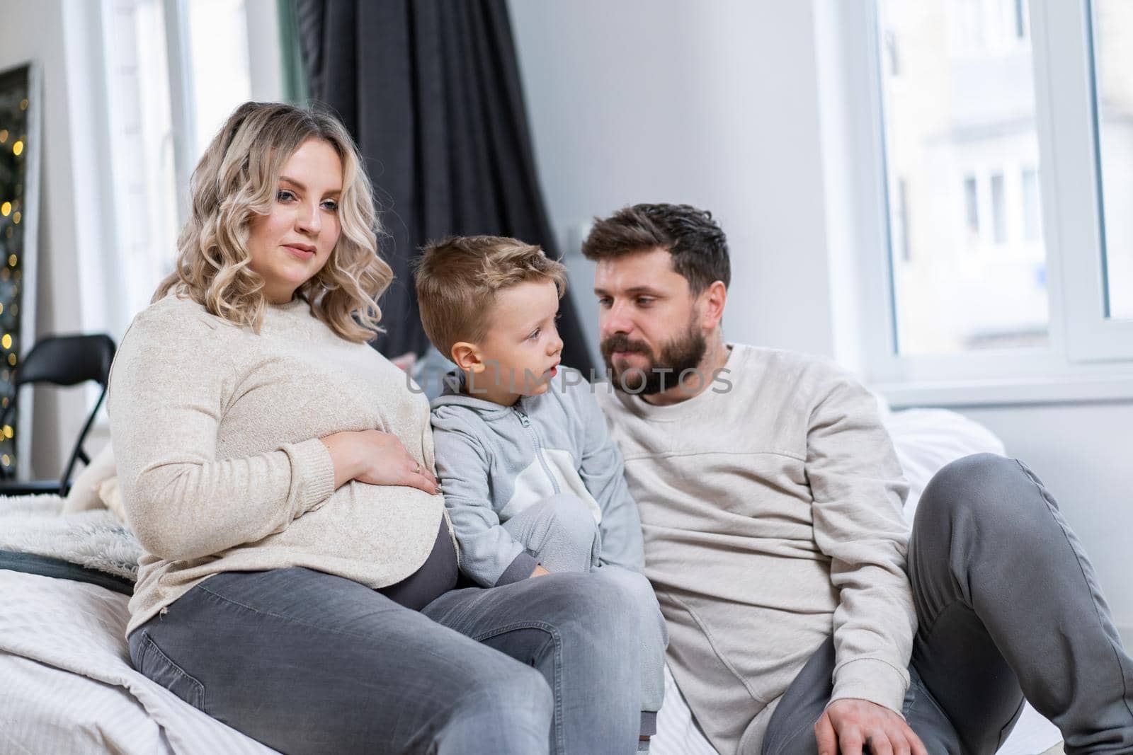 Happy family concept Mother father and little son have fun at home Caucasian family indoors Pregnant mom beard dad and funny little boy