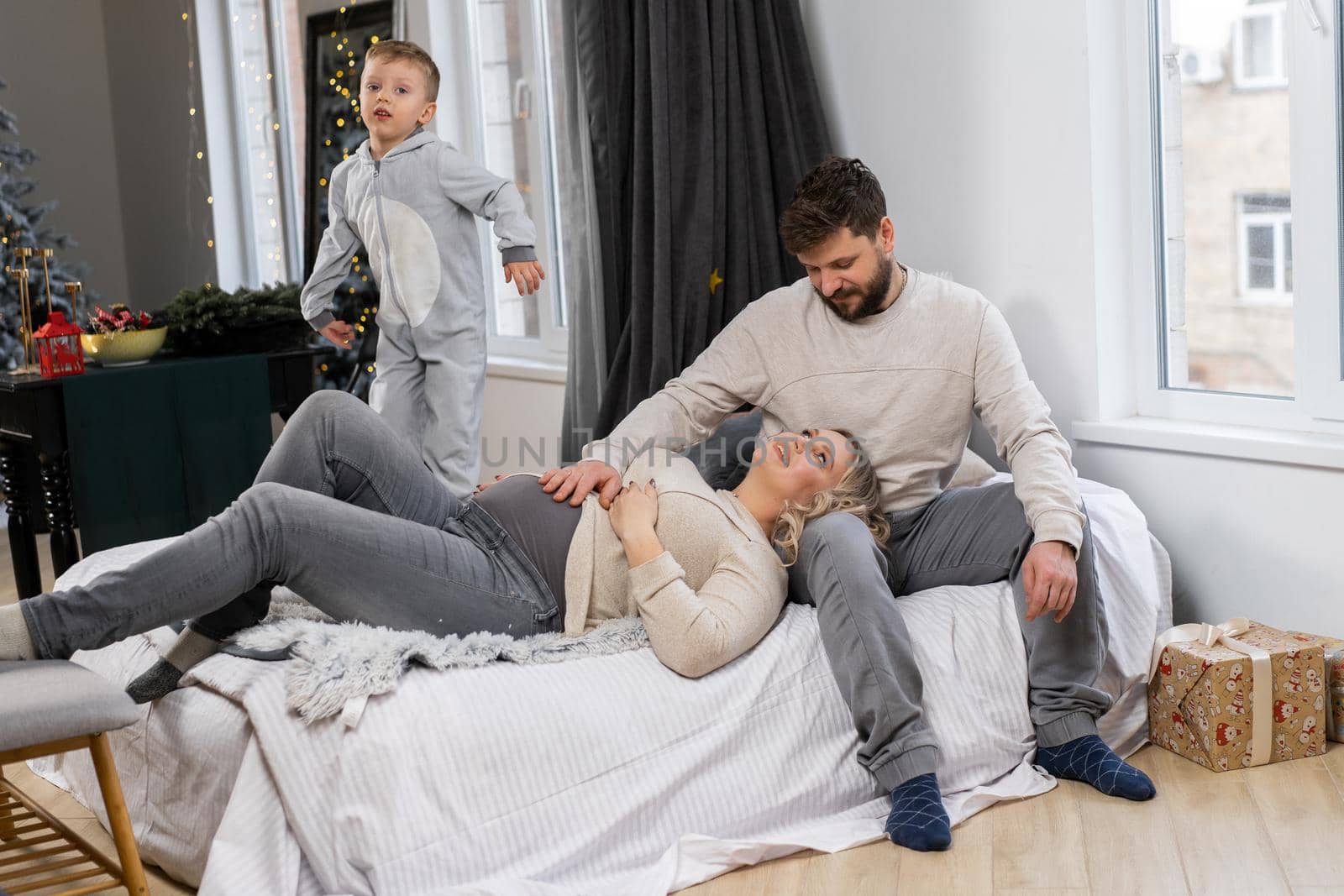 Happy family concept Mother father and little son have fun at home Caucasian family indoors Pregnant mom beard dad and funny little boy lie on the couch