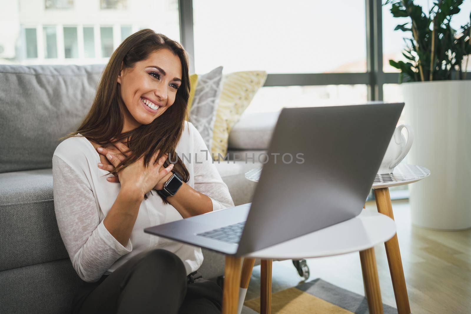 Smiling young woman having online consultation with psychotherapist at her home on laptop.