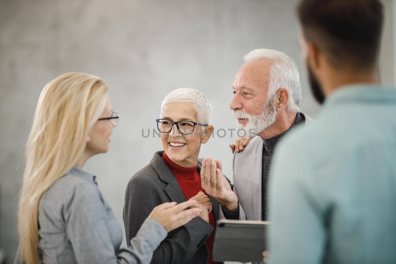 A group of confident business people using digital tablet  and having a discussion with each other during the meeting in a modern office.