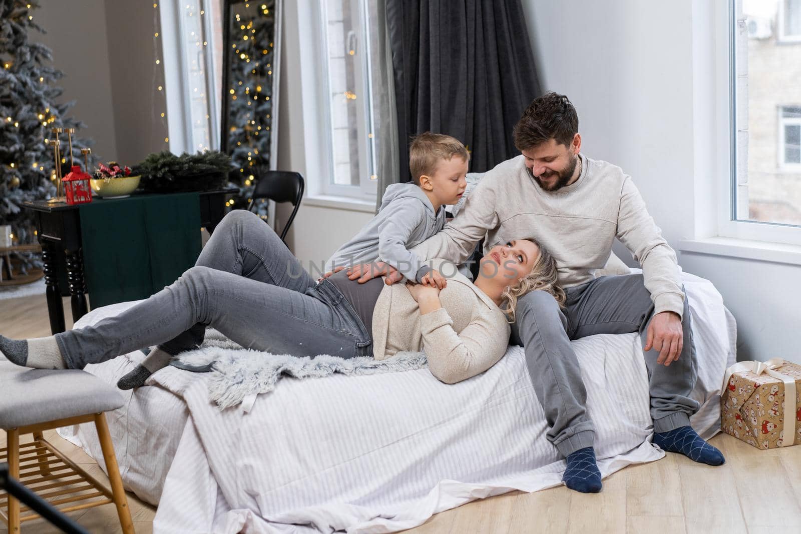 Happy family concept Mother father and little son have fun at home Caucasian family indoors Pregnant mom beard dad and funny little boy lie on the couch