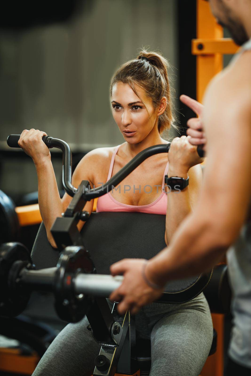 An attractive young woman working out with personal trainer at the cross training gym.