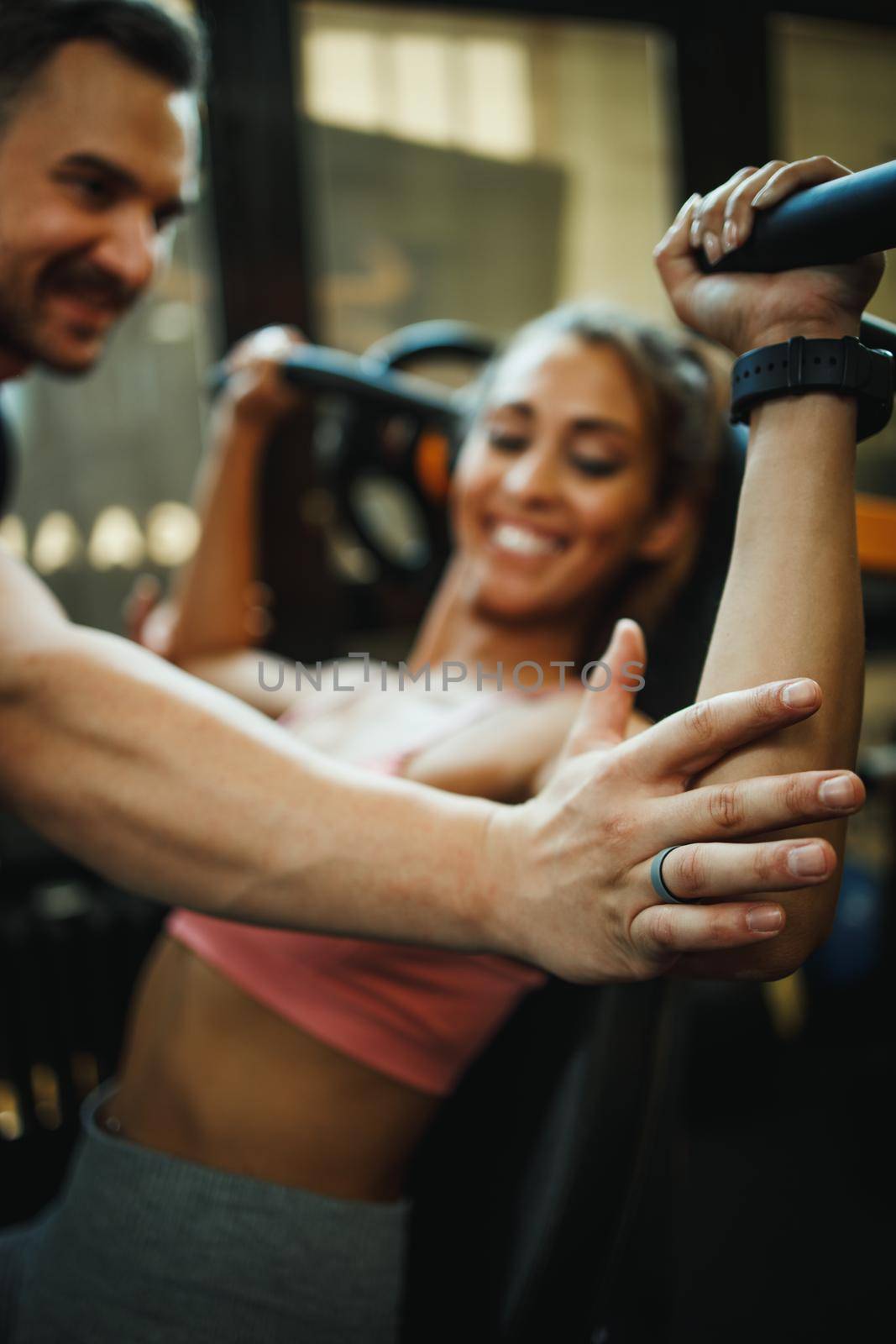 An attractive young woman working out with personal trainer at the cross training gym.
