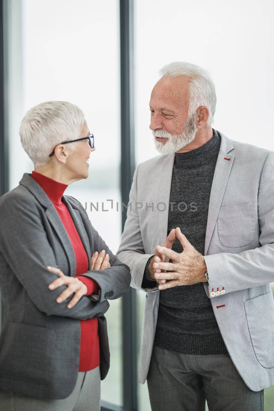 A two confident senior business people walking and talking in a modern office.