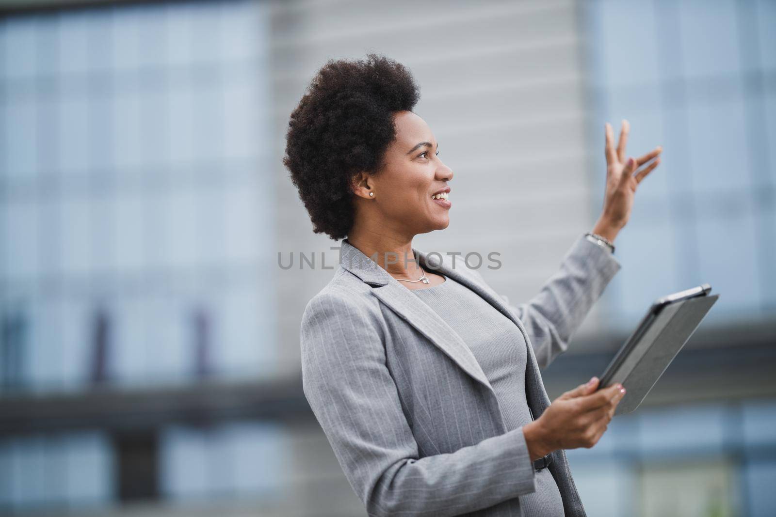 Portrait of a successful black business woman making video call on a digital tablet in front a corporate building.