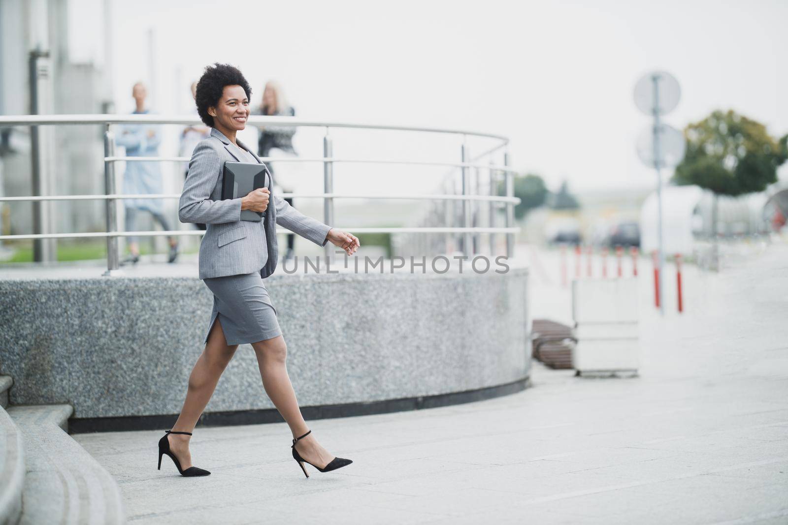 A successful black business woman while walking down a stairs in front a corporate building.
