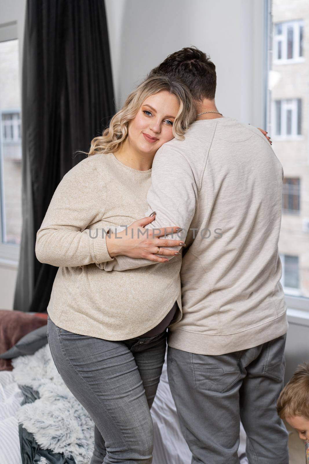 Happy family concept. Husband hug belly pregnant wife standing indoor living room near sofa Caucasian man and woman pregnancy and new life concept. Love and care