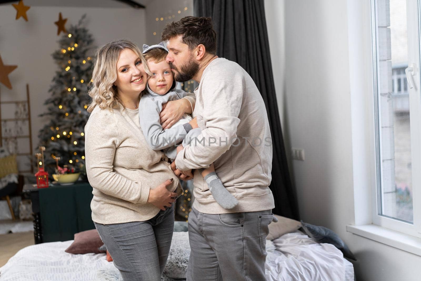 Happy family concept Mother father and little son have fun at home Caucasian family indoors Pregnant mom beard dad and funny little boy
