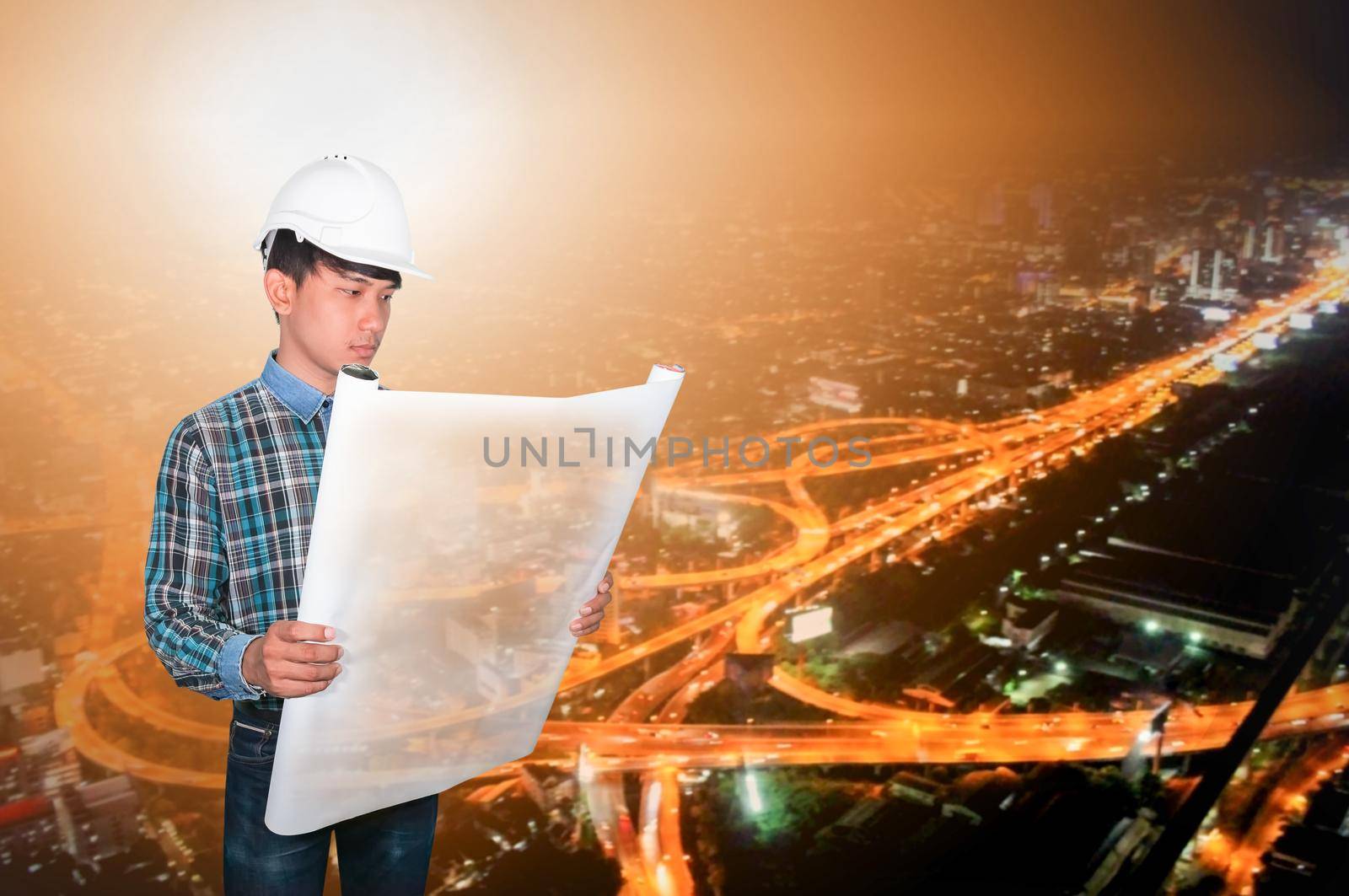 Engineer open hold blueprints in construction concept with night cityscape Blurred background by pramot