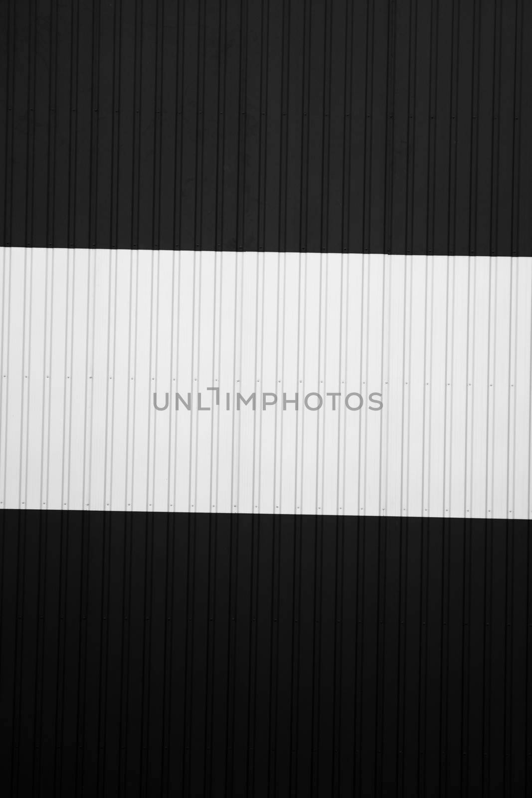 Black and white corrugated iron sheet used as a facade of a warehouse or factory. Texture of a seamless corrugated zinc sheet metal aluminum facade. Architecture. Metal texture