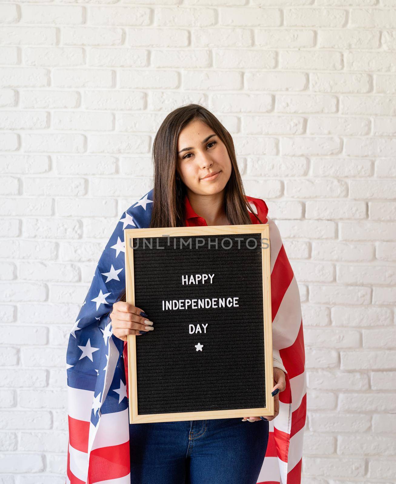 woman with american flag holding letter board with words Happy Independence Day by Desperada