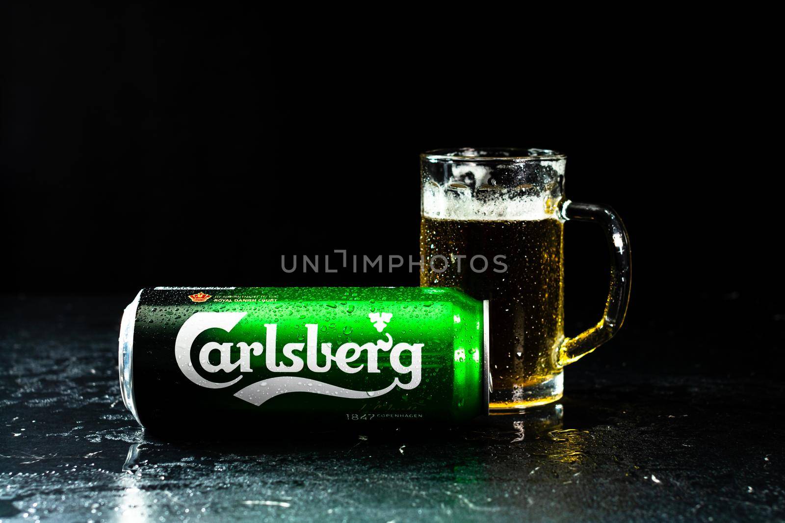 Can of Carlsberg beer and beer glass on dark background. Illustrative editorial photo shot in Bucharest, Romania, 2021 by vladispas