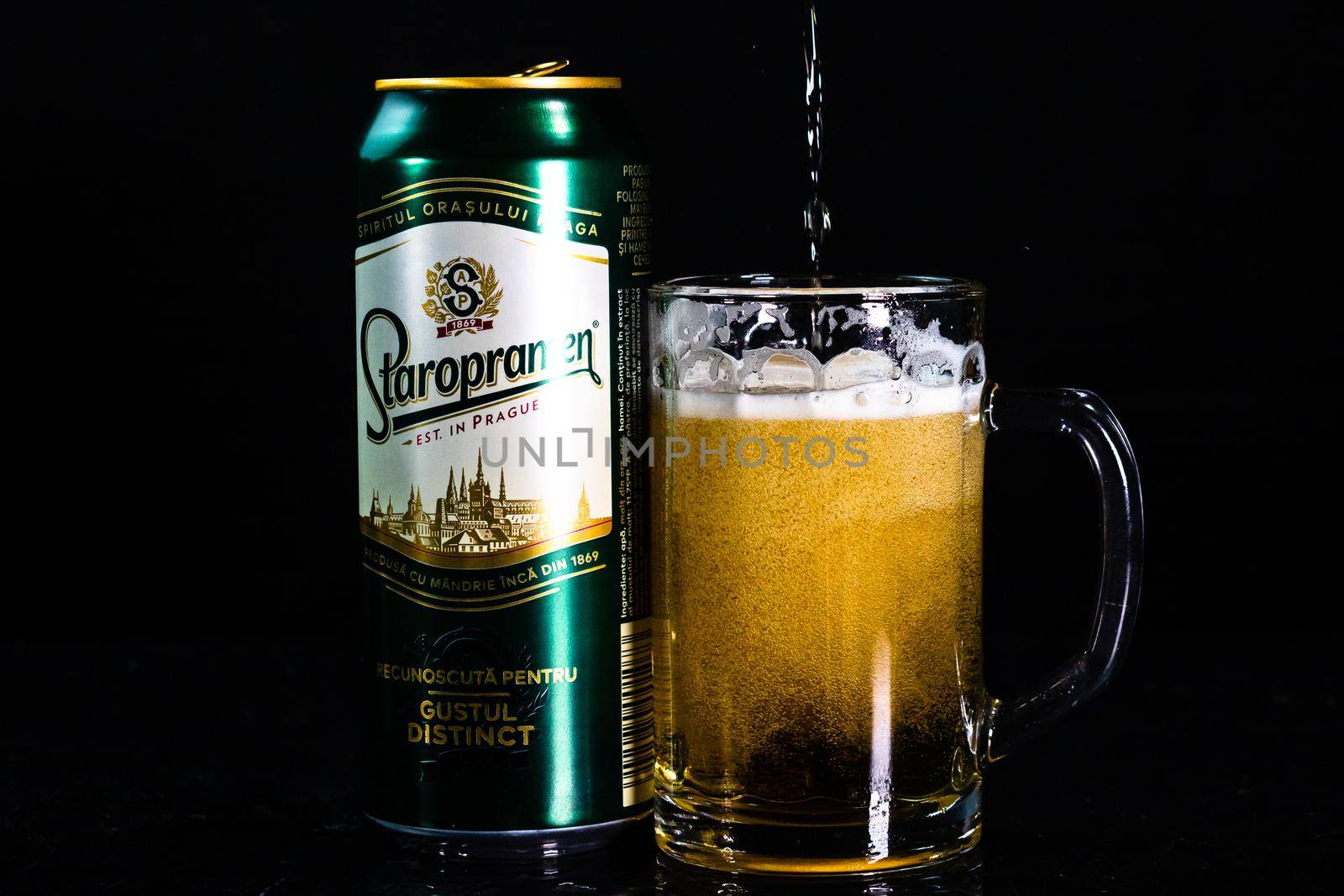 Can of Staropramen beer and beer glass on dark background. Illustrative editorial photo shot in Bucharest, Romania, 2021 by vladispas